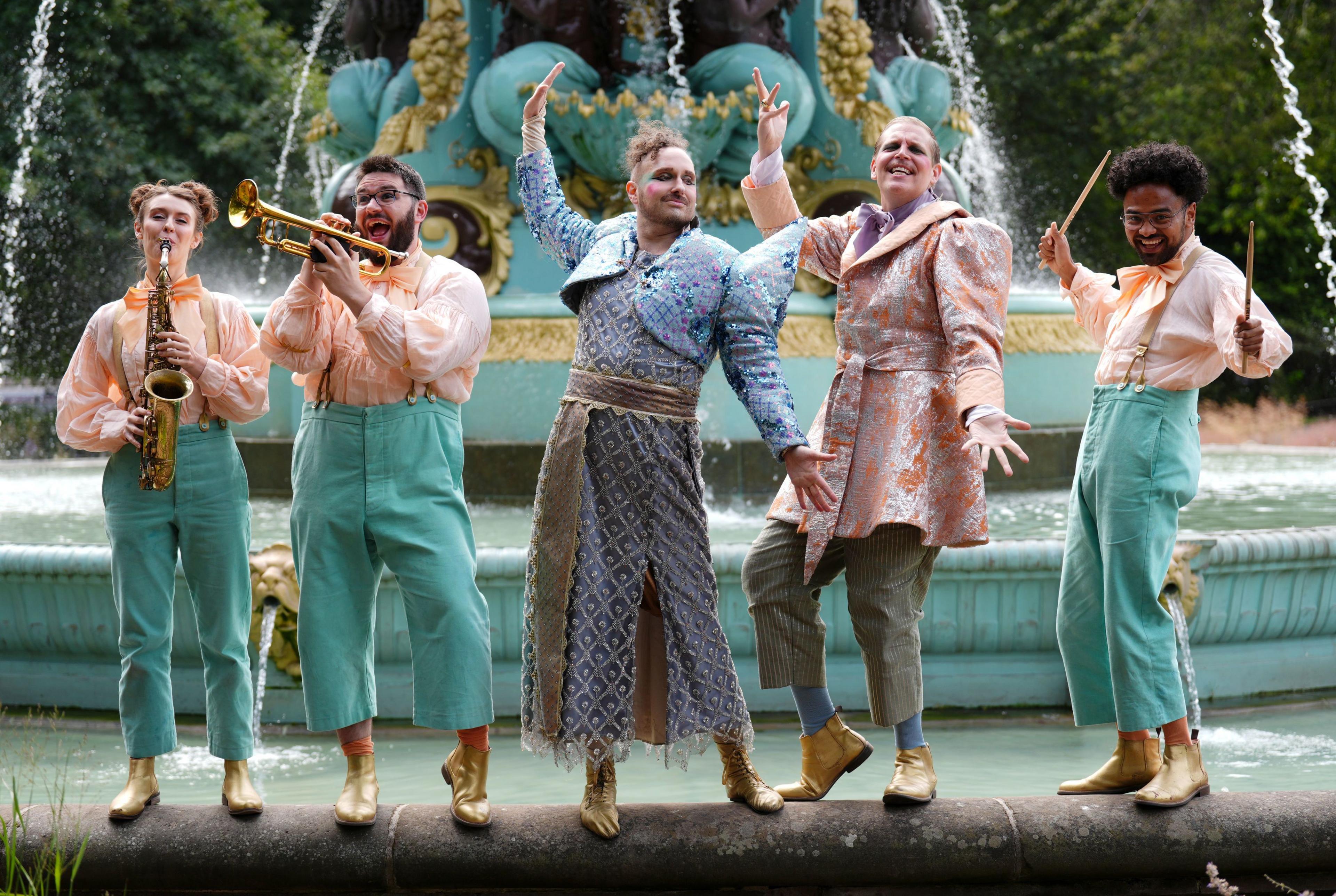 Five musicians from How to Win Against History match the green tones of the Ross Fountain, in green costumes as they pose on the edge of the round Victorian iron structure, holding up their instruments.
