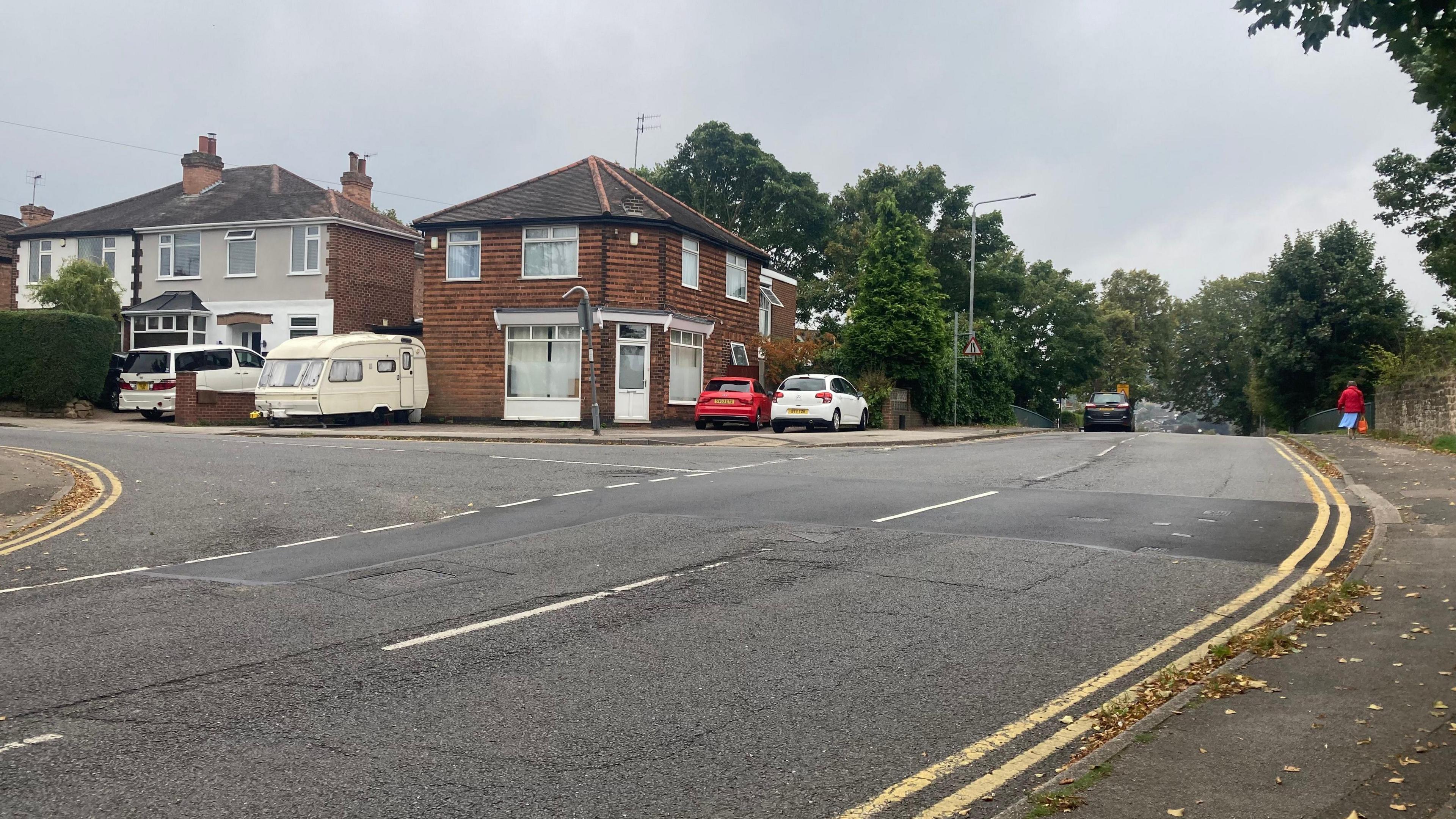 The brow of a hill on Thackerays Lane with houses and road markings in view