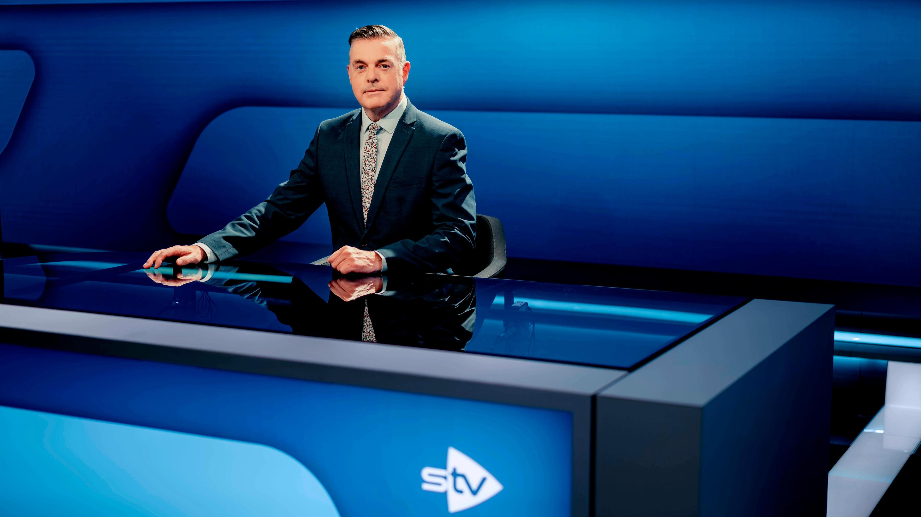 Tormod Macleòid na shuidhe aig deasc naidheachd STV
