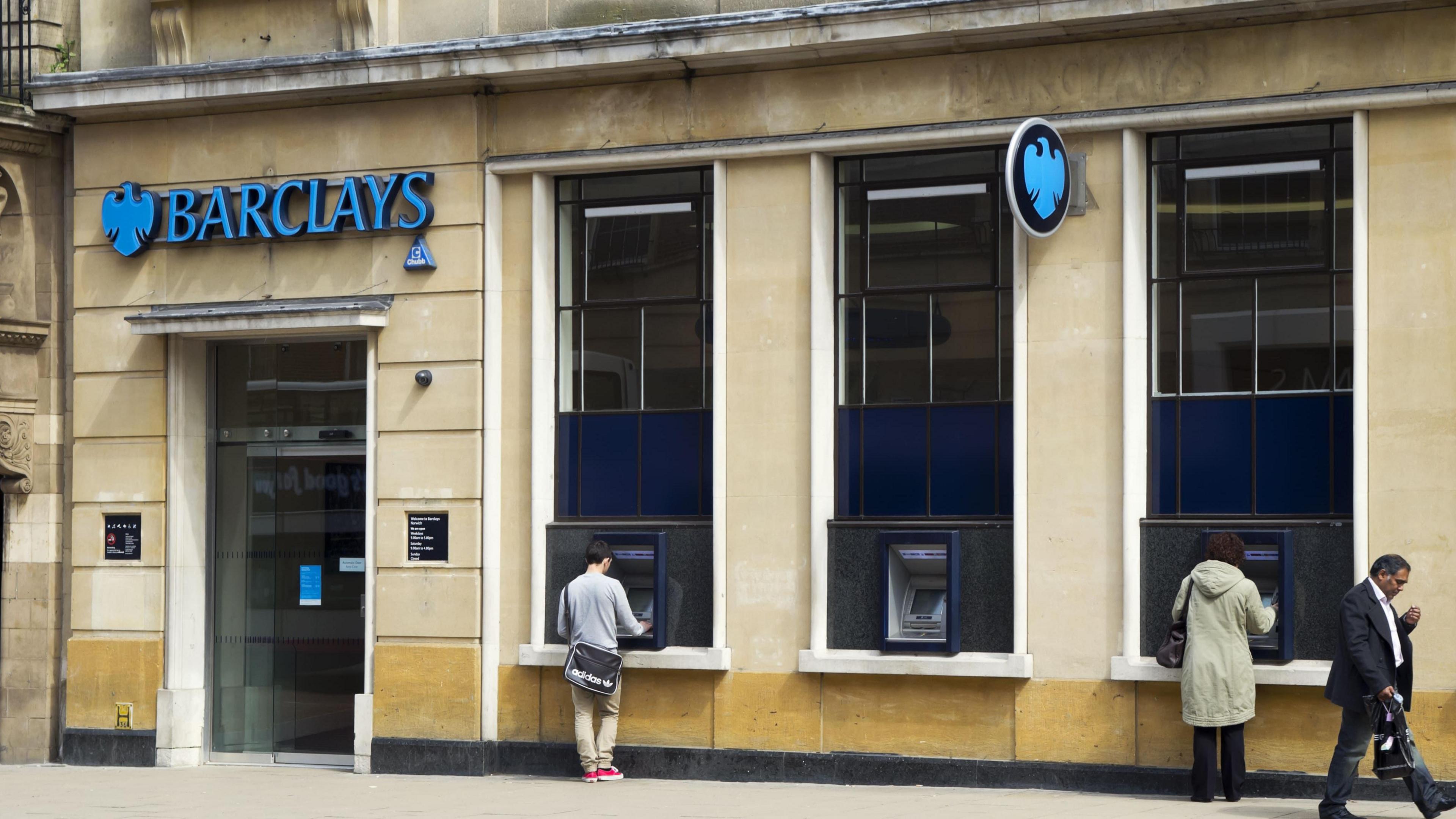 Barclays branch exterior - the bank's sign is visible with some people standing in front of the bank, which is a large sandstone building. 