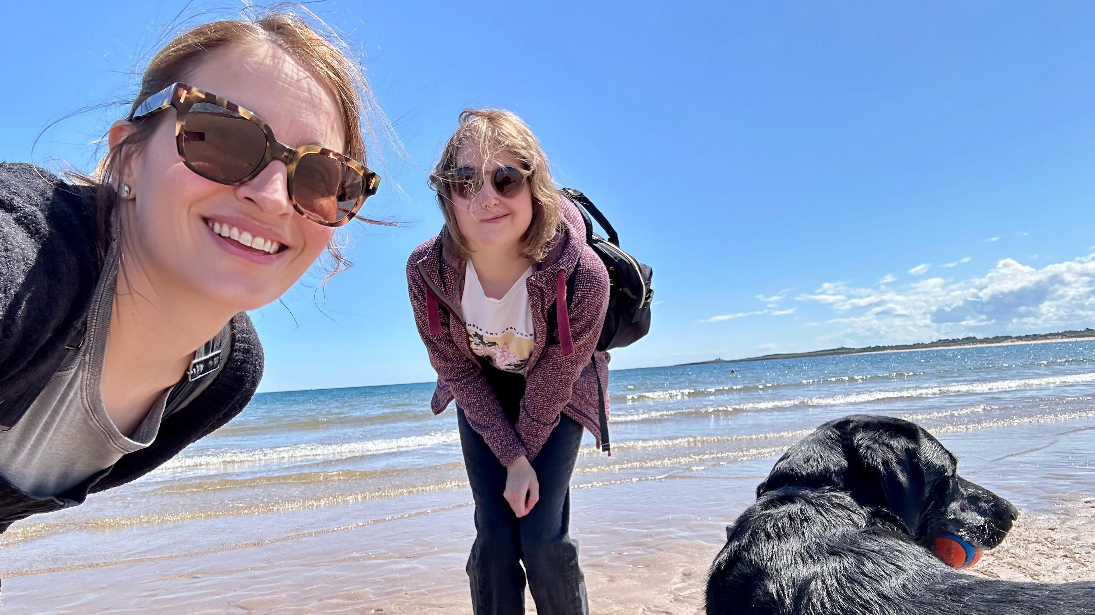 Adele Wilson-Hope and her daughter Bella at the beach with their dog.