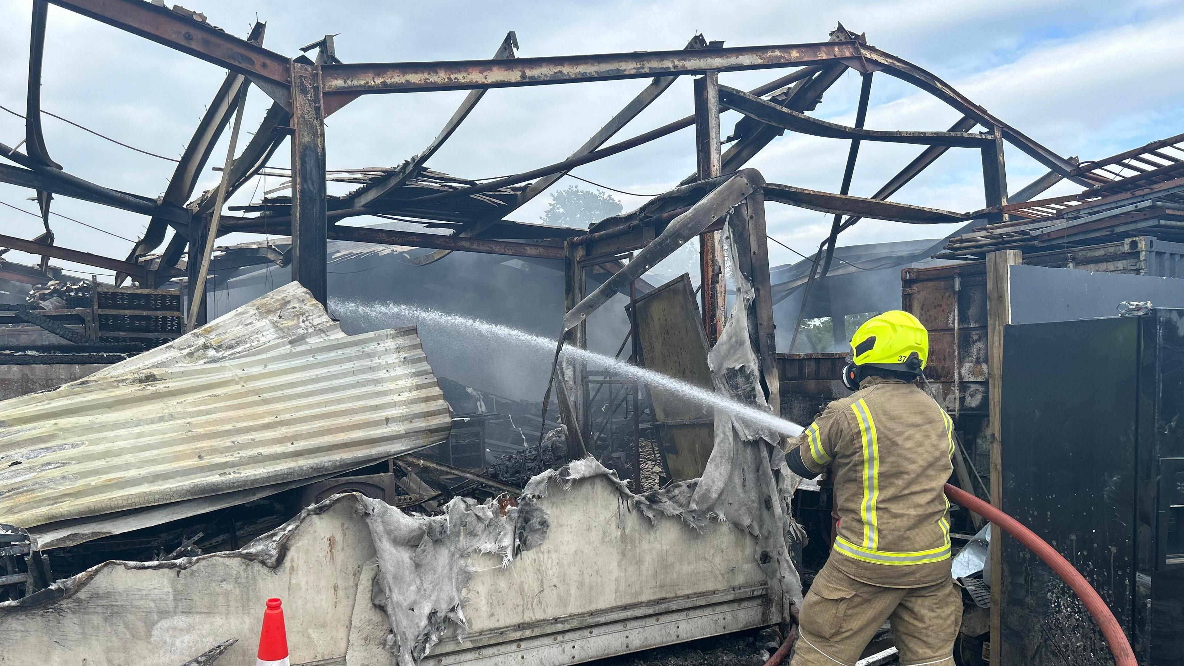 A fire engine seen from the back with the smoking barn in the background