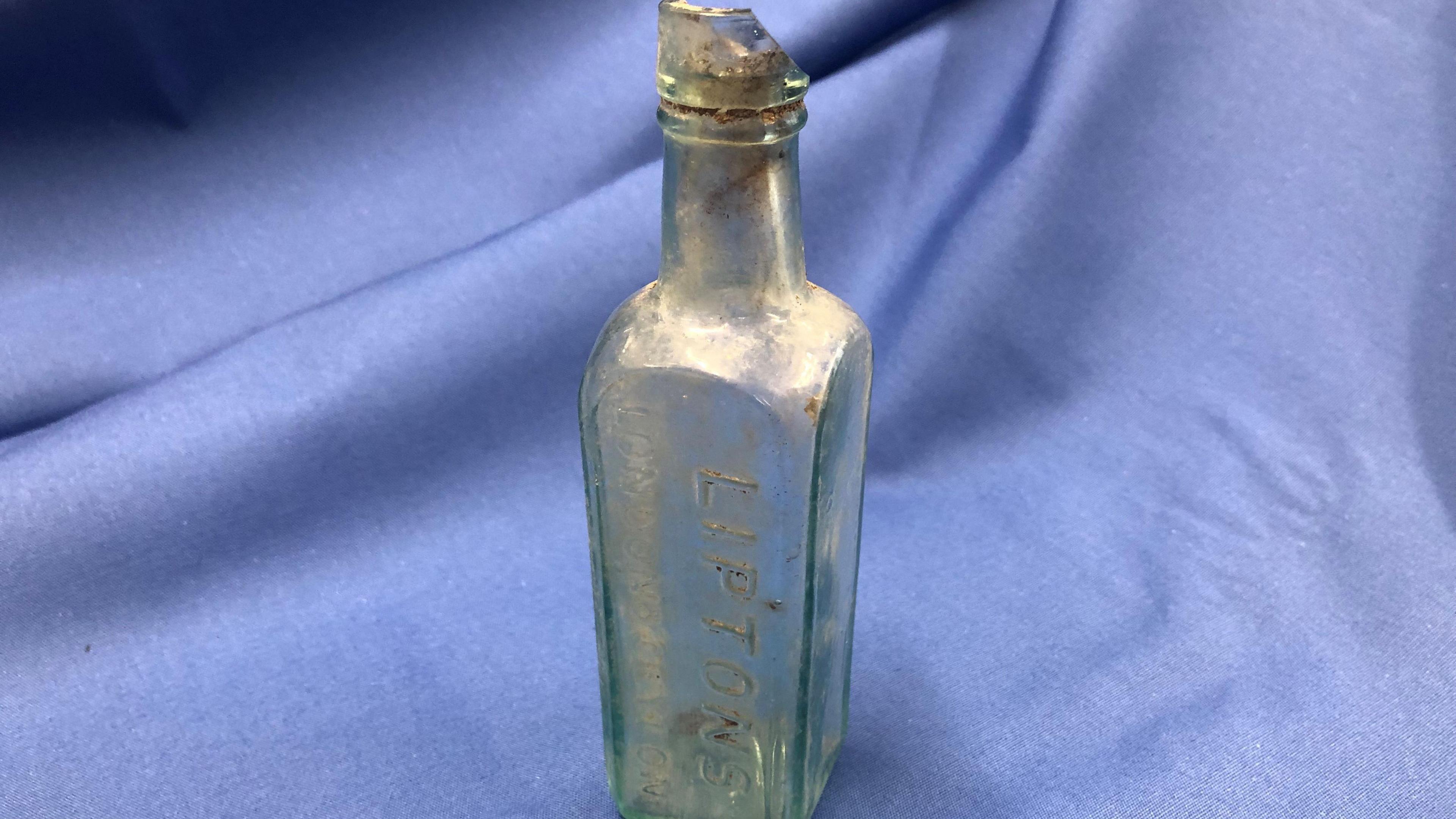 A glass Lipton’s drinks bottle on a blue cloth. 