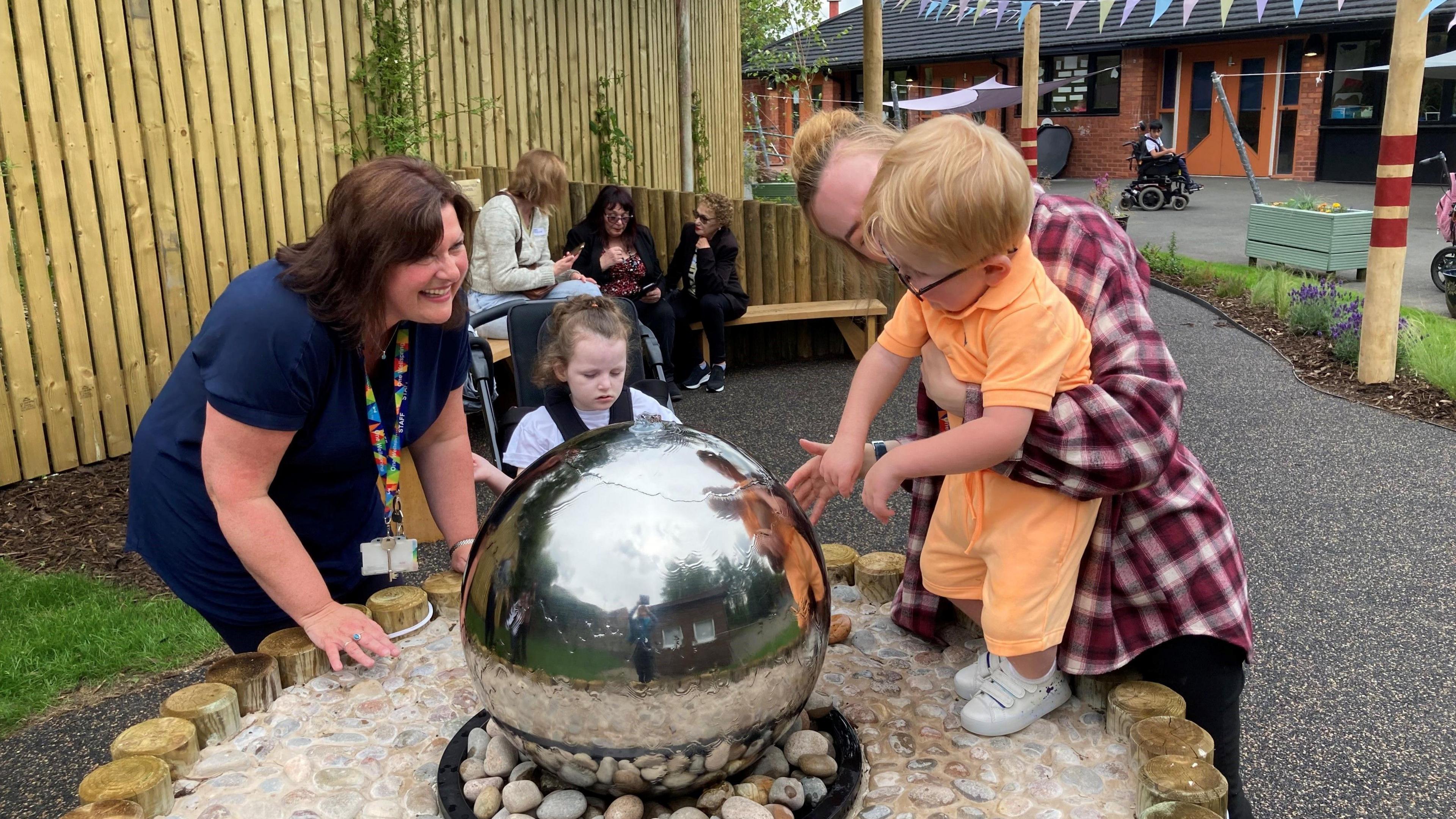 A child plays with the water feature in the memorial garden