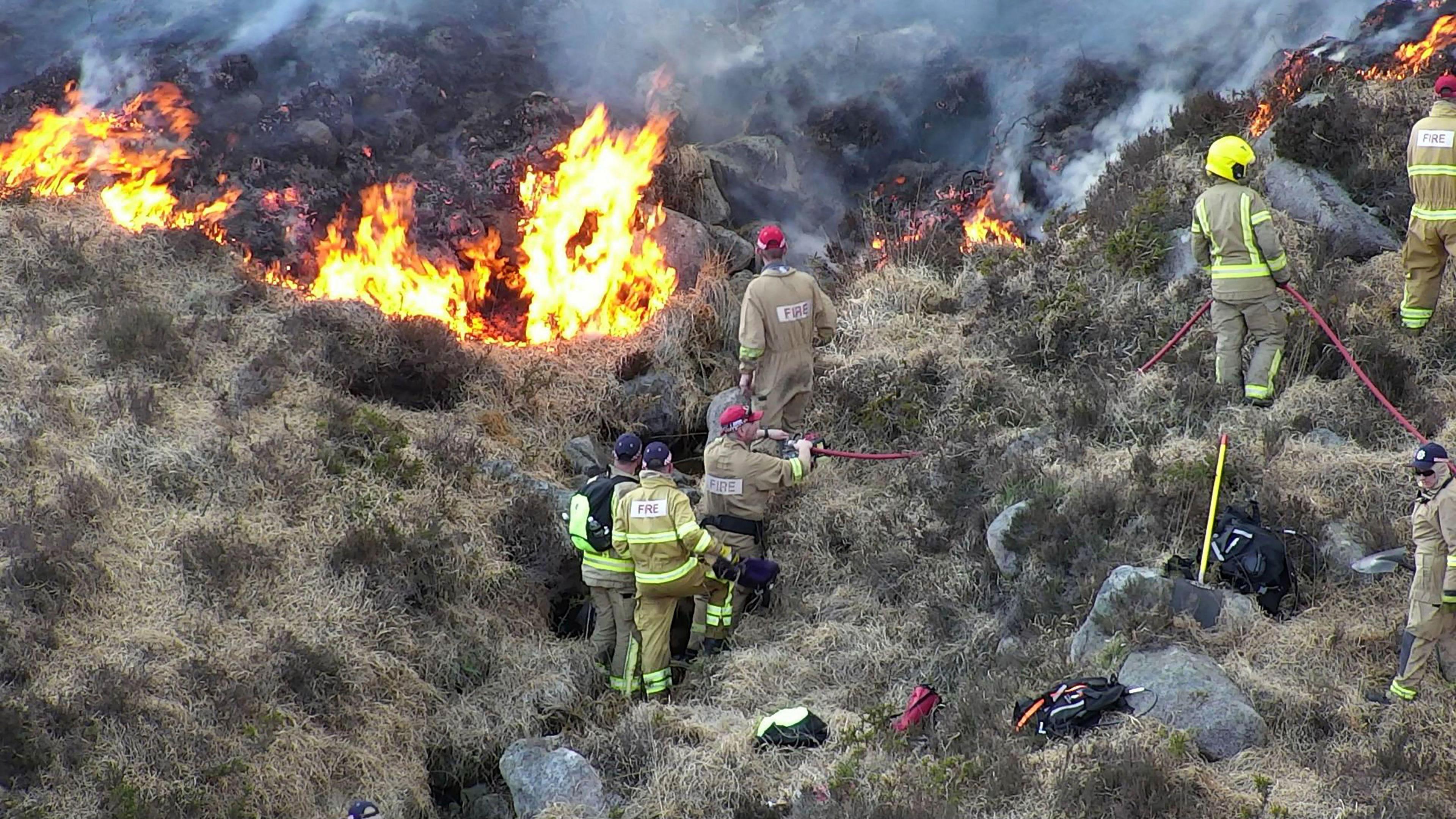A group of firefighters tackle a blaze on the side of a mountain