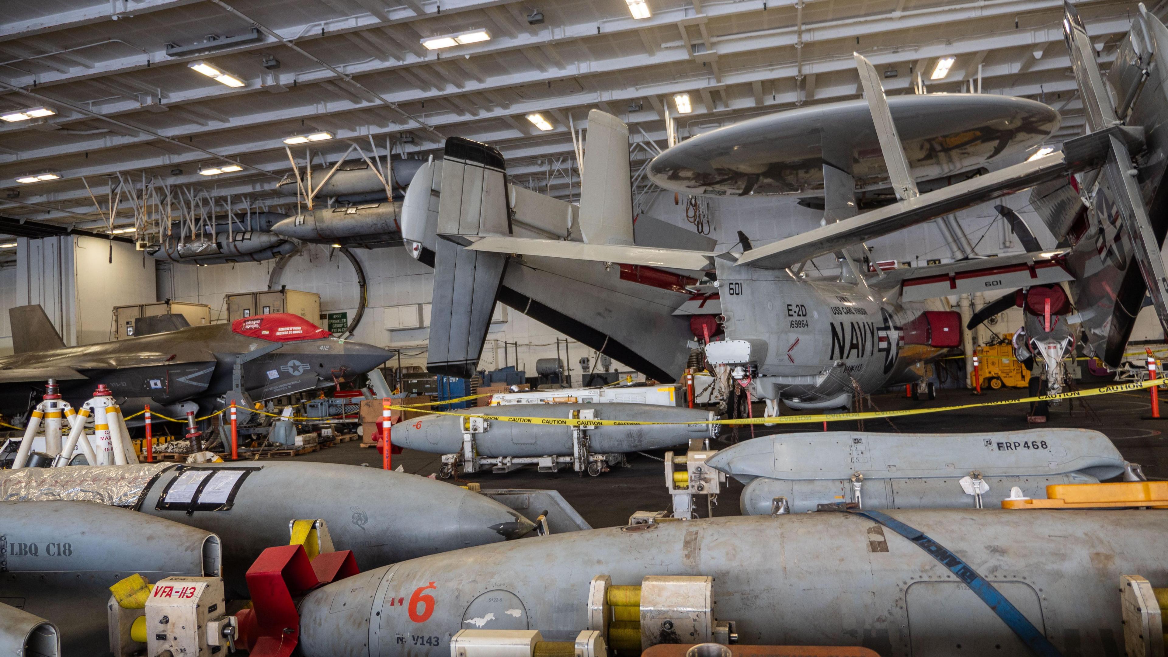 The maintenance hangar under the flight deck on the USS Carl Vinson with an F35C Raptor fighter, left, and an E2C Hawkeye early warning aircraft, right