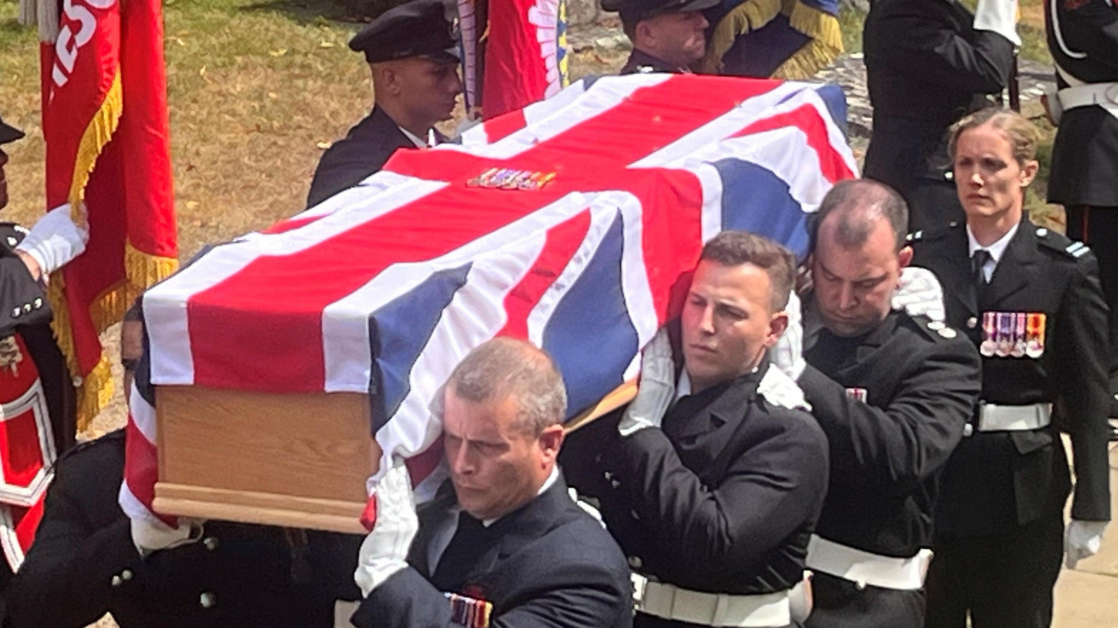 Fire service pall bearers carrying the Union flag-draped coffin
