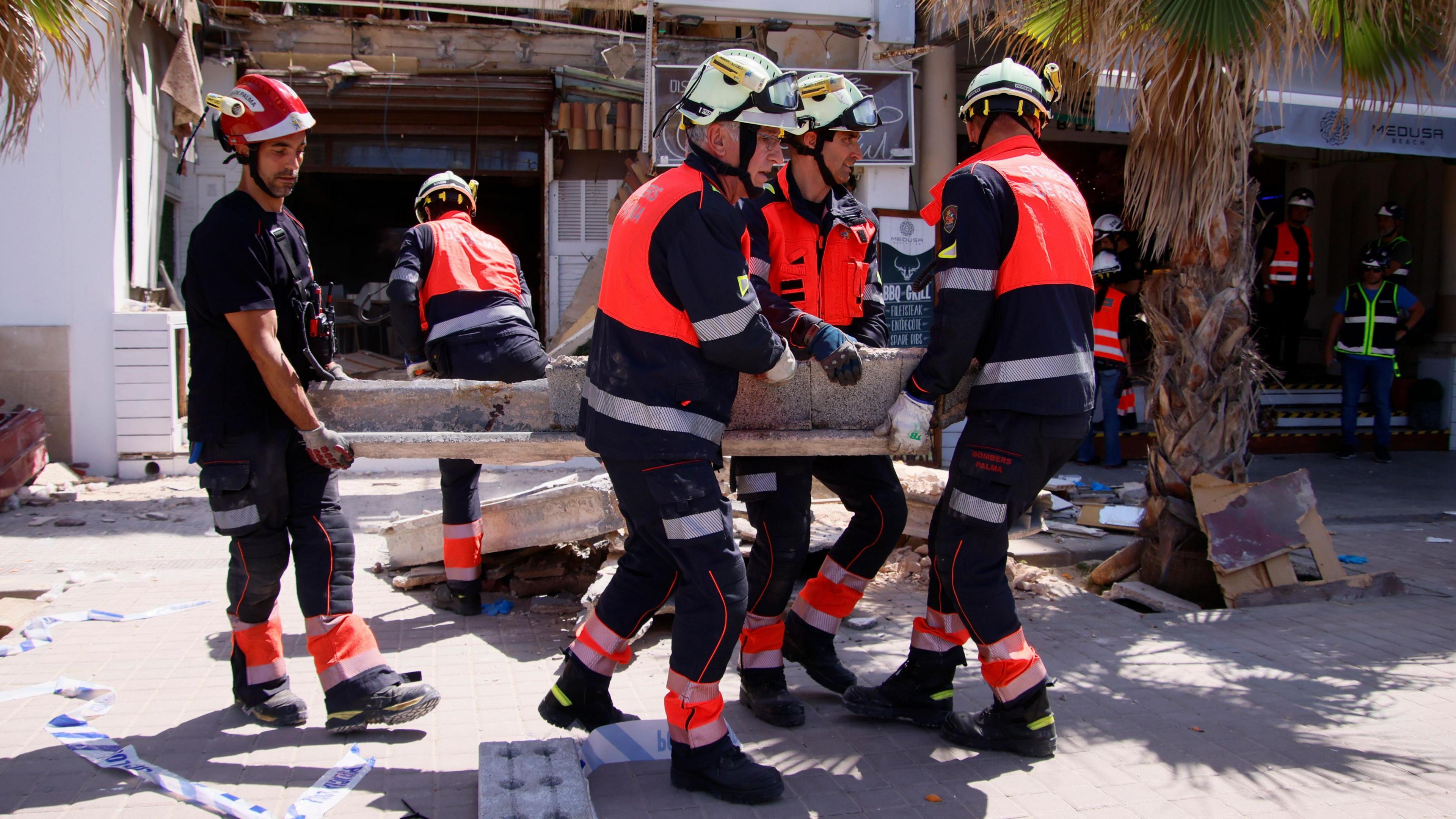 Firefighters carrying a large bit of debris