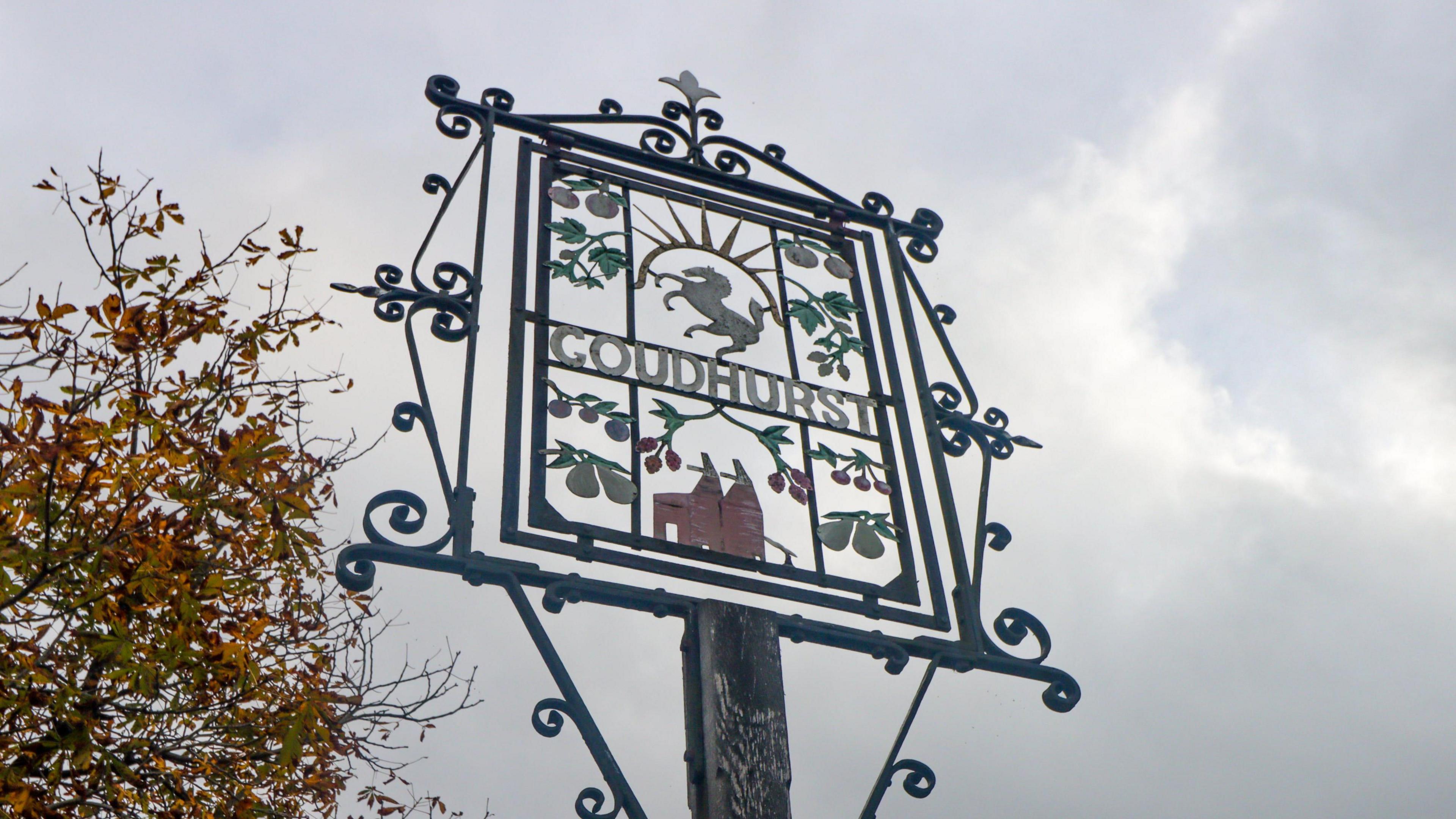 A metal village sign which says "Goudhurst" in the middle.