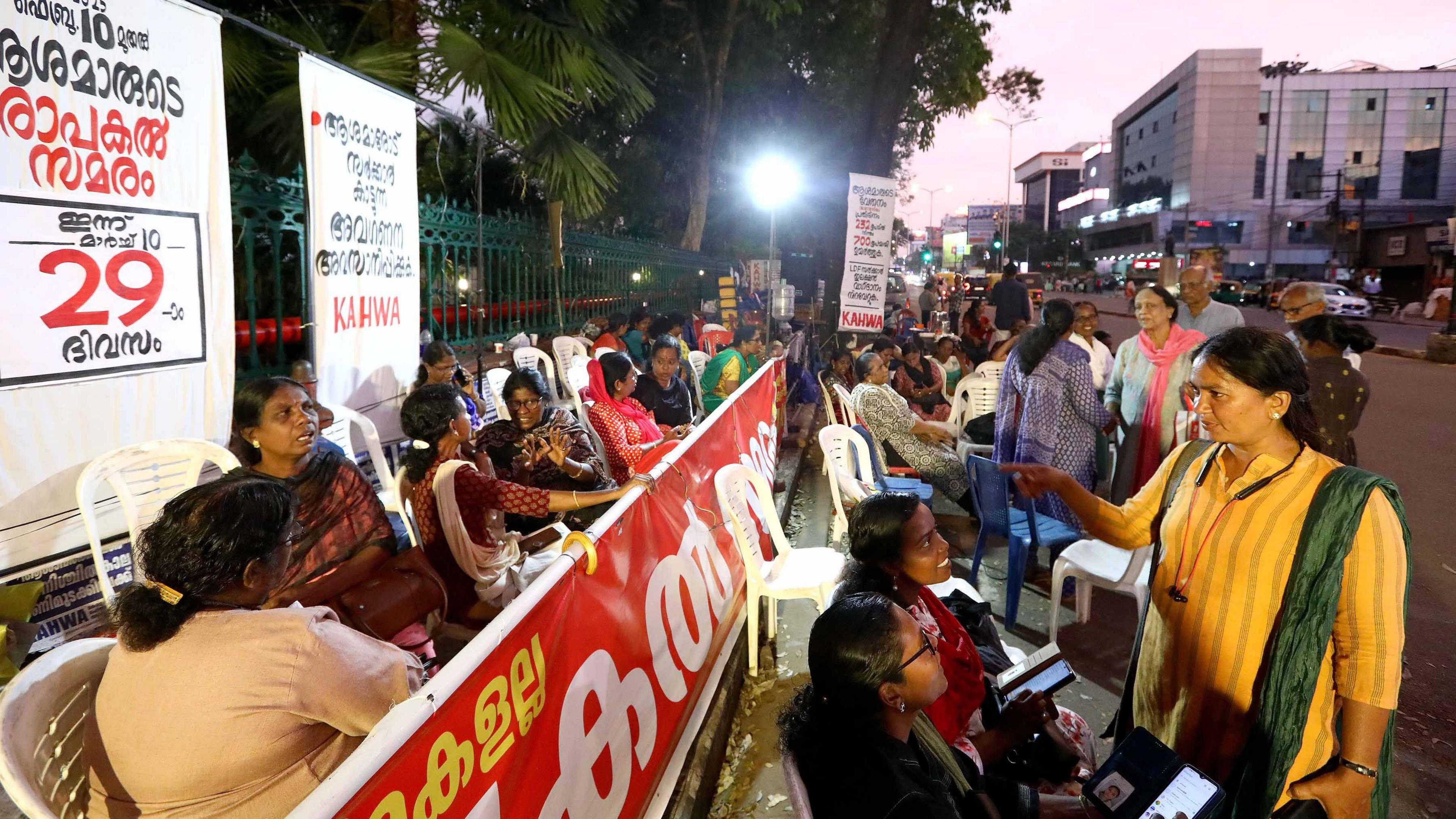 A glimpse of the protest site in front of the Kerala Secretariat where protesters have camped out on white plastic chairs with placards and banners.