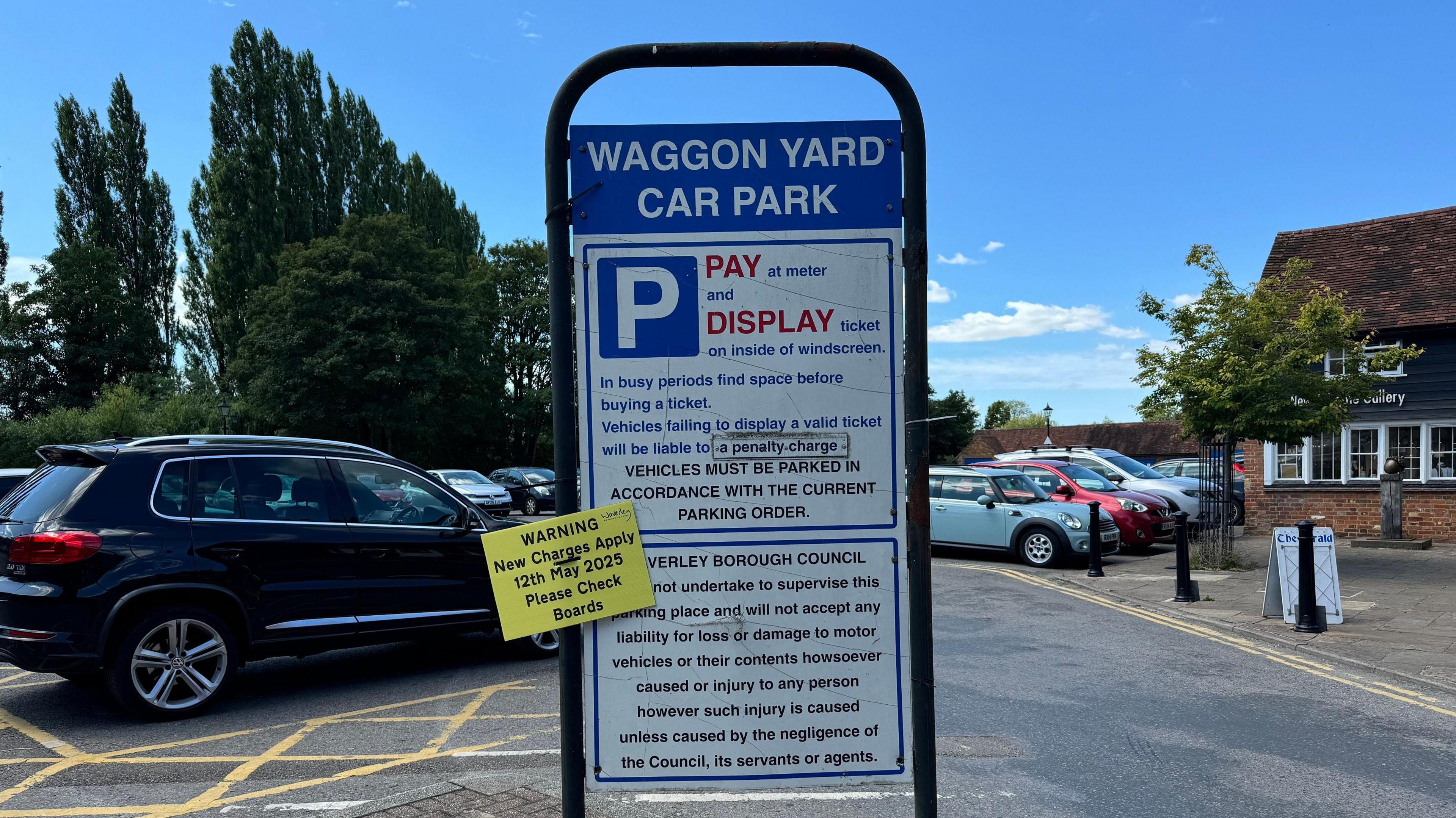 A sign at the entrance of the Waggon Yard Car Park in Farnham. It says 'WAGGON YARD CAR PARK' in white letters on a blue background. Below on a white sign in blue letters it says: 'PAY at meter and DISPLAY ticket on inside of windscreen. 
