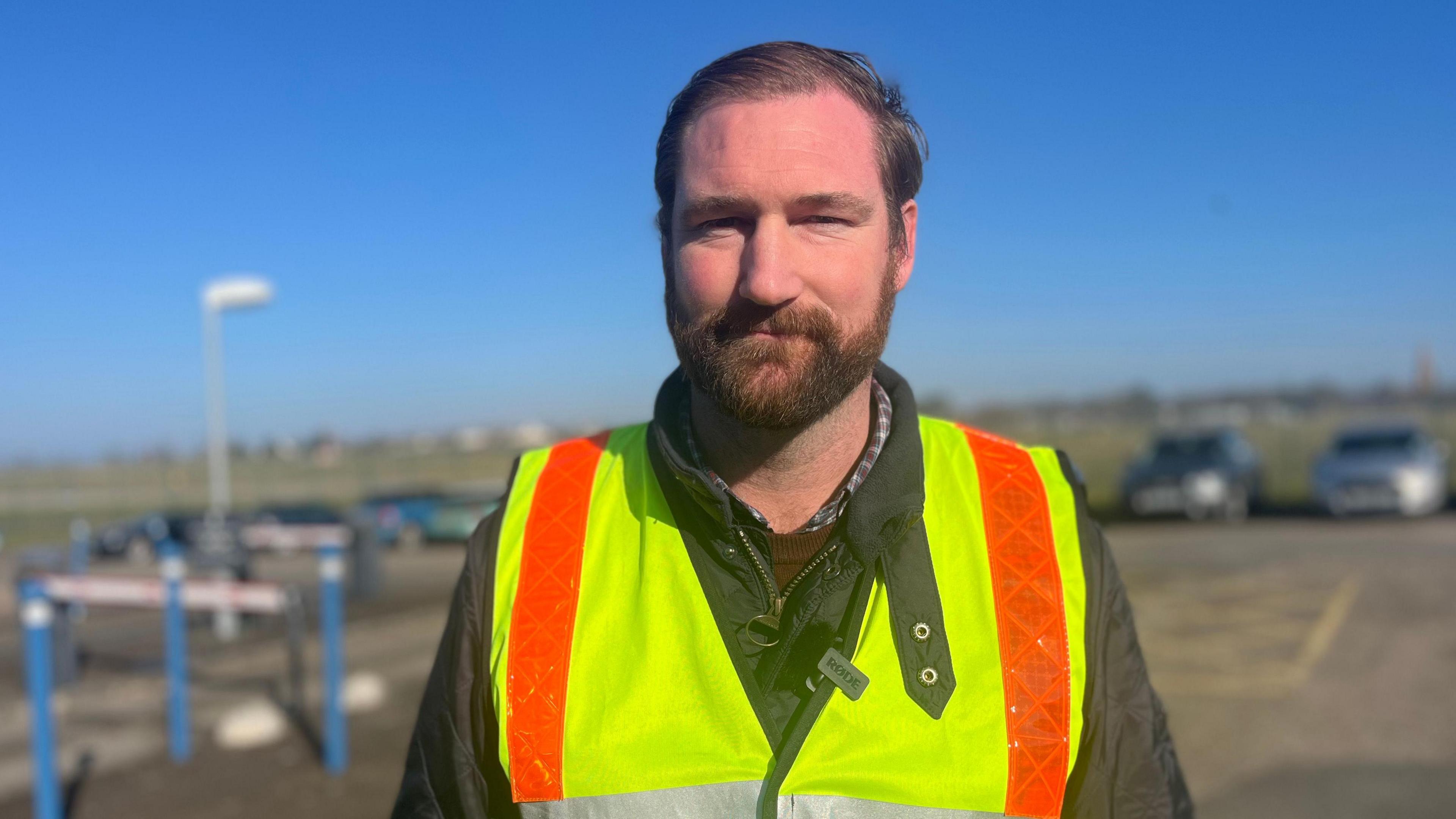 Airport operations Director Ashley Maggs wearing a high vis vest and looking at the camera in a car park.