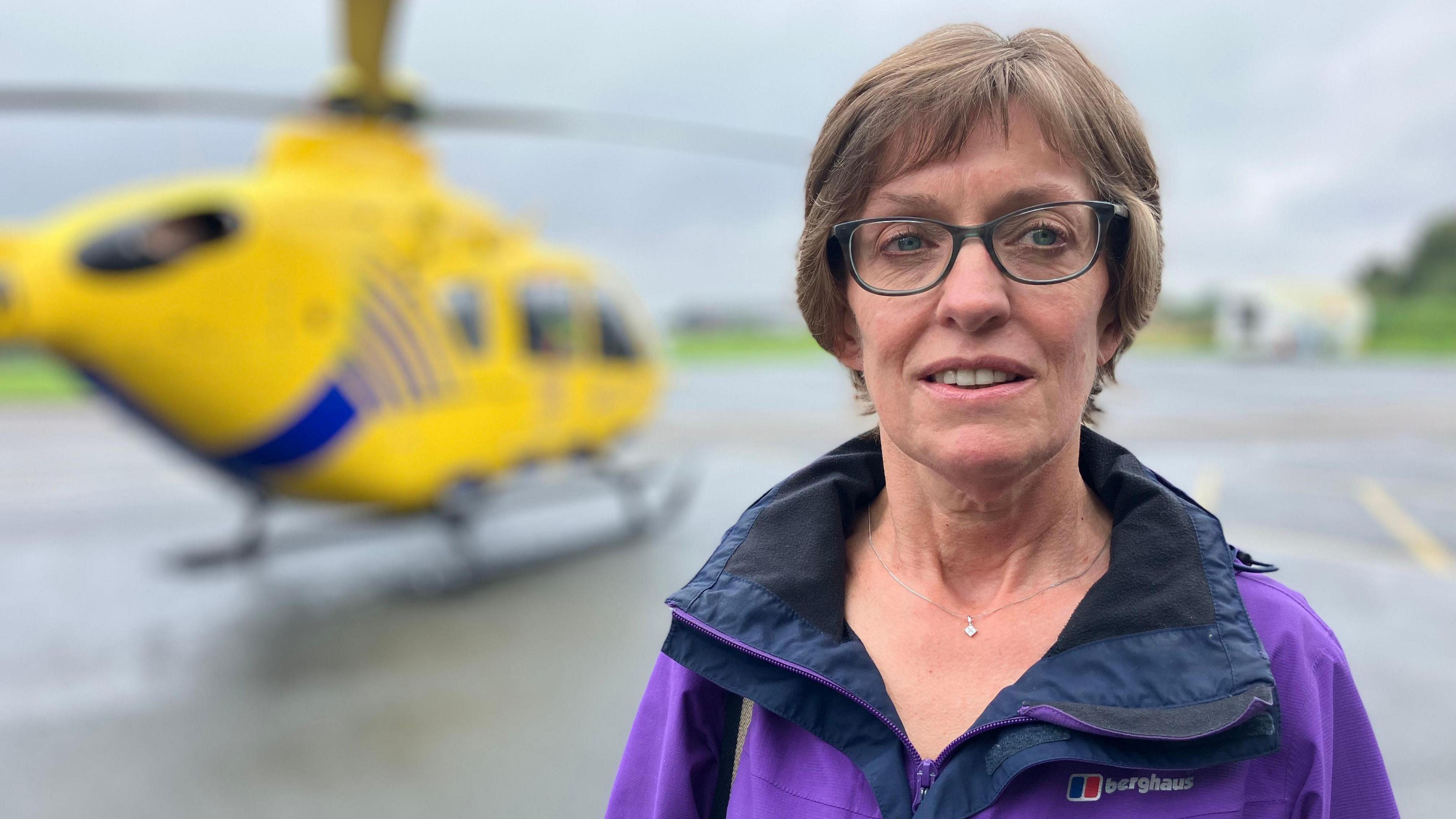 Rachel Hilton in a purple jacket in front of the air ambulance