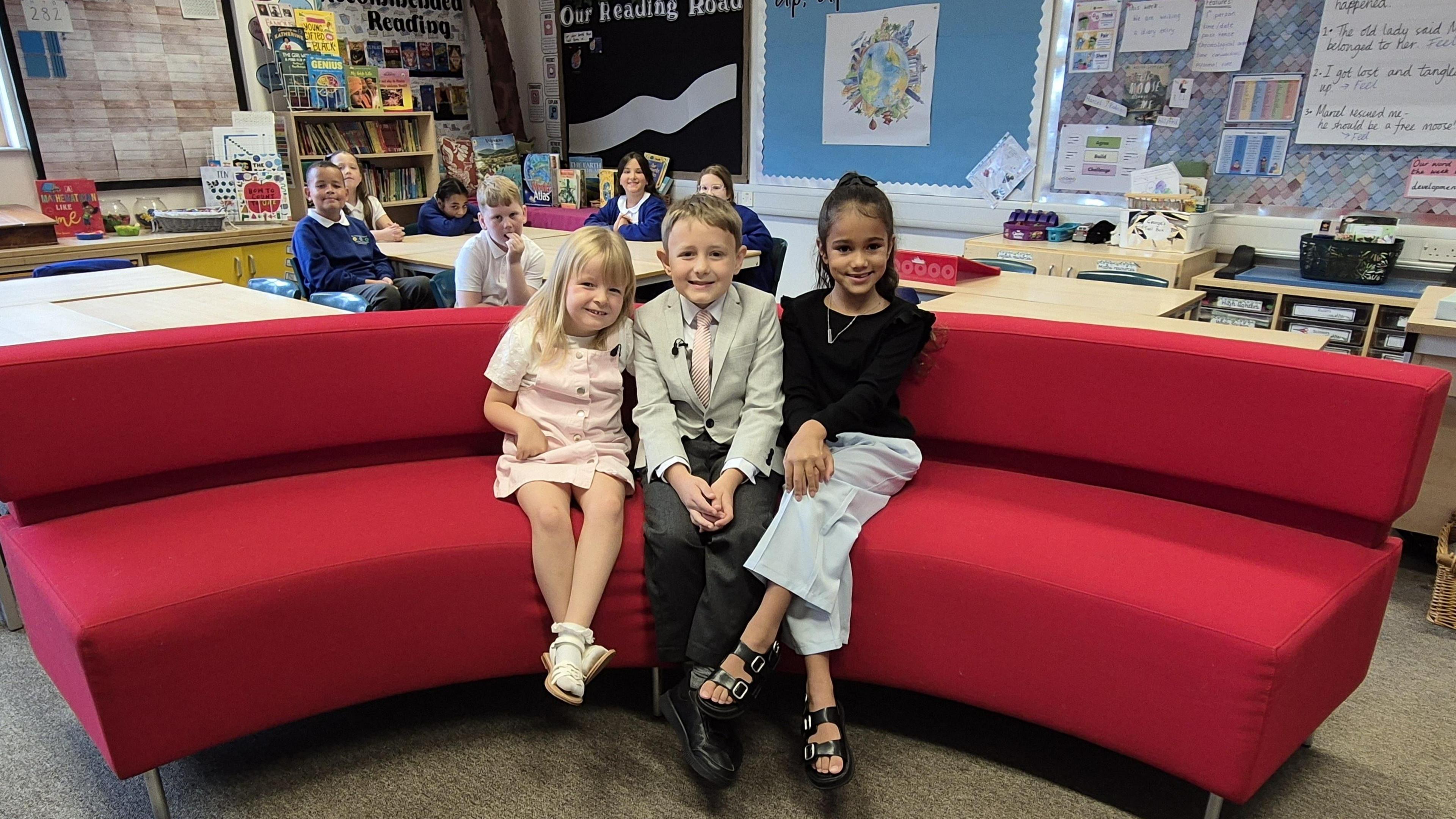 Three pupils from Hadley Learning Community Primary in Telford sitting on the red sofa, dressed up as presenters Mary Rhodes, Nick Owen and Shefali Oza