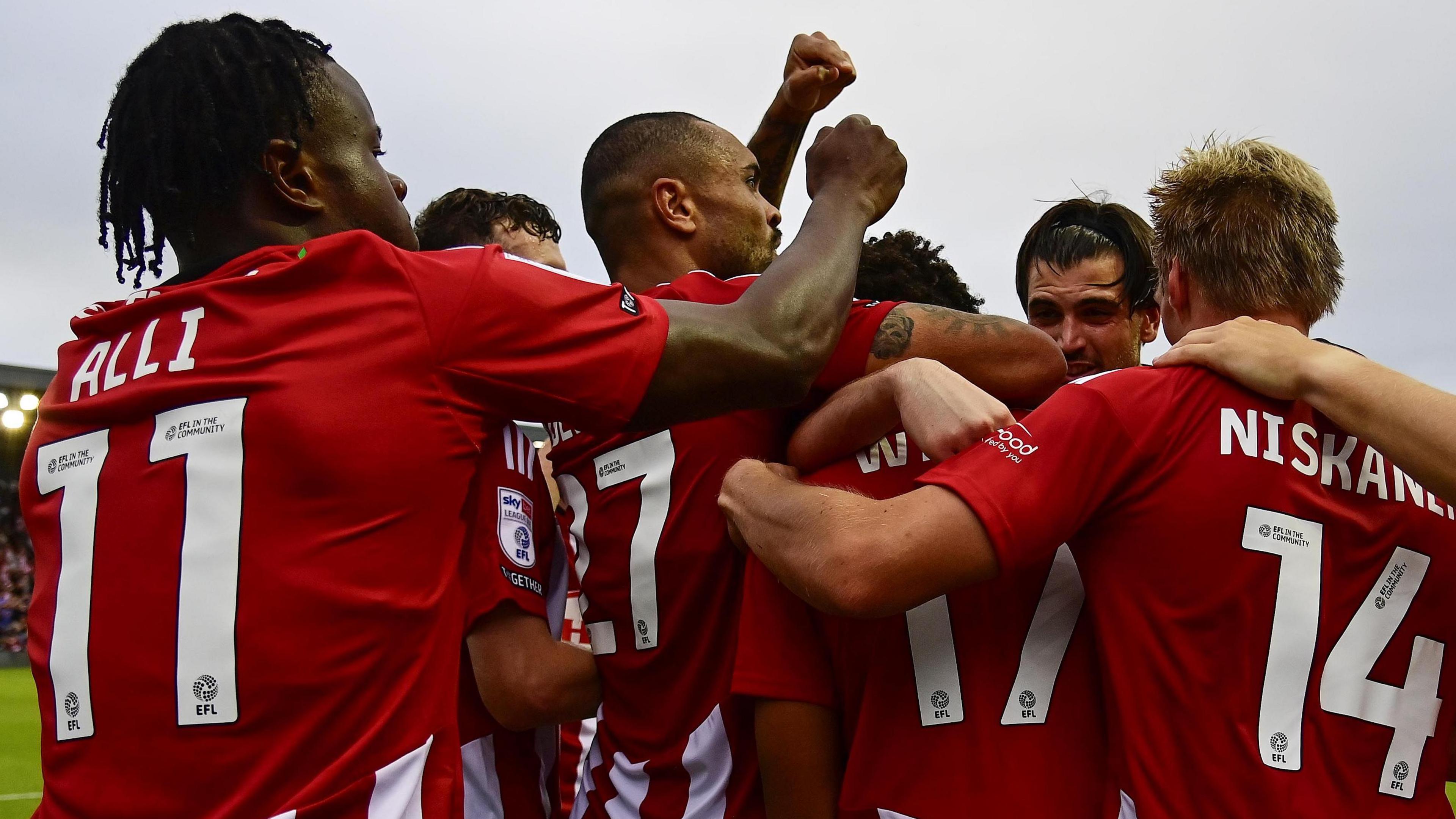 Exeter players mob Caleb Watts after his second-half goal against Rotherham