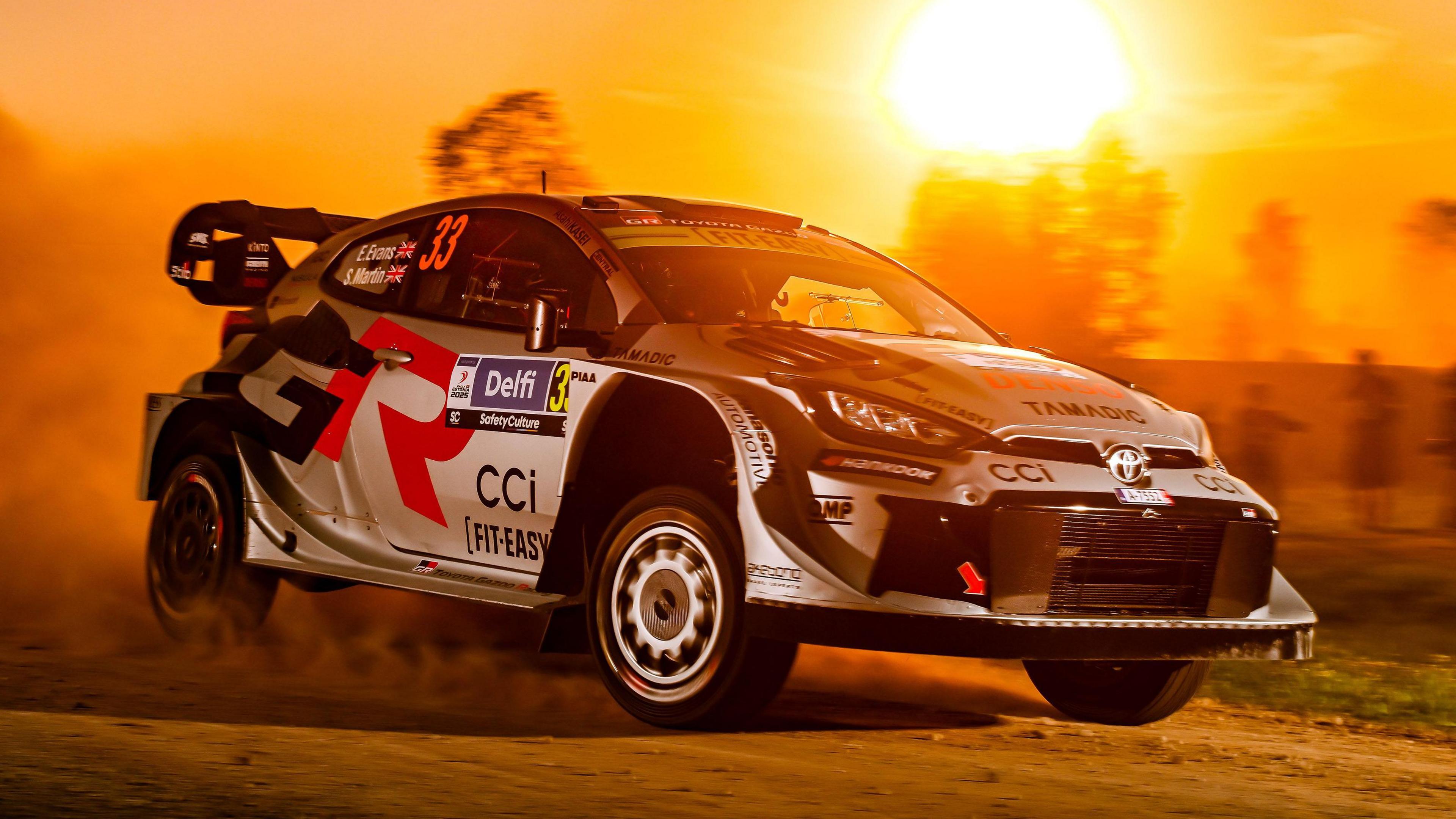 Car rali Elfyn Evans yn gyrru mewn machlud haul