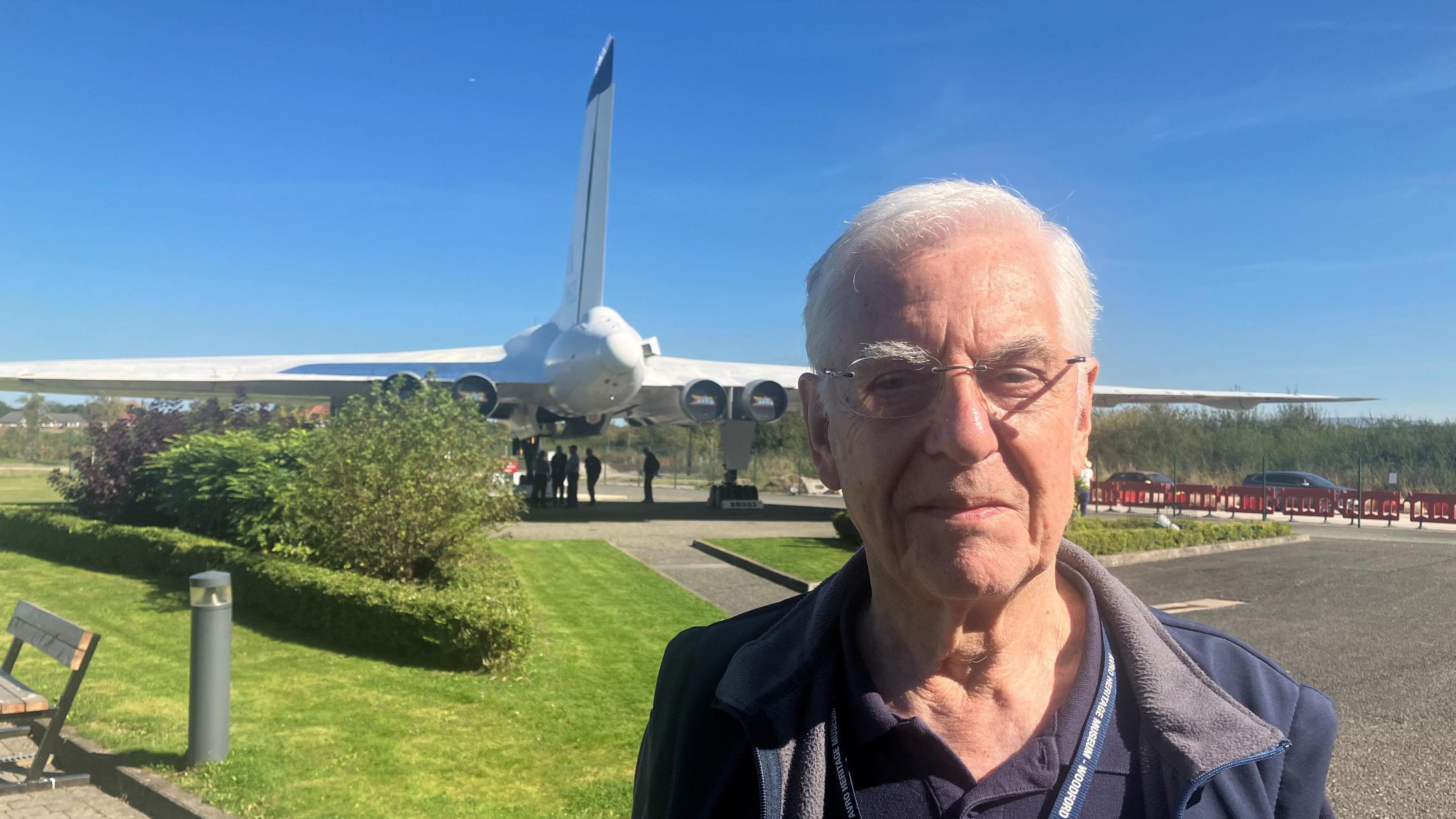 Photo of former worker John Nichol, standing outside the museum, with an Avro Vulcan nuclear bomber in the background