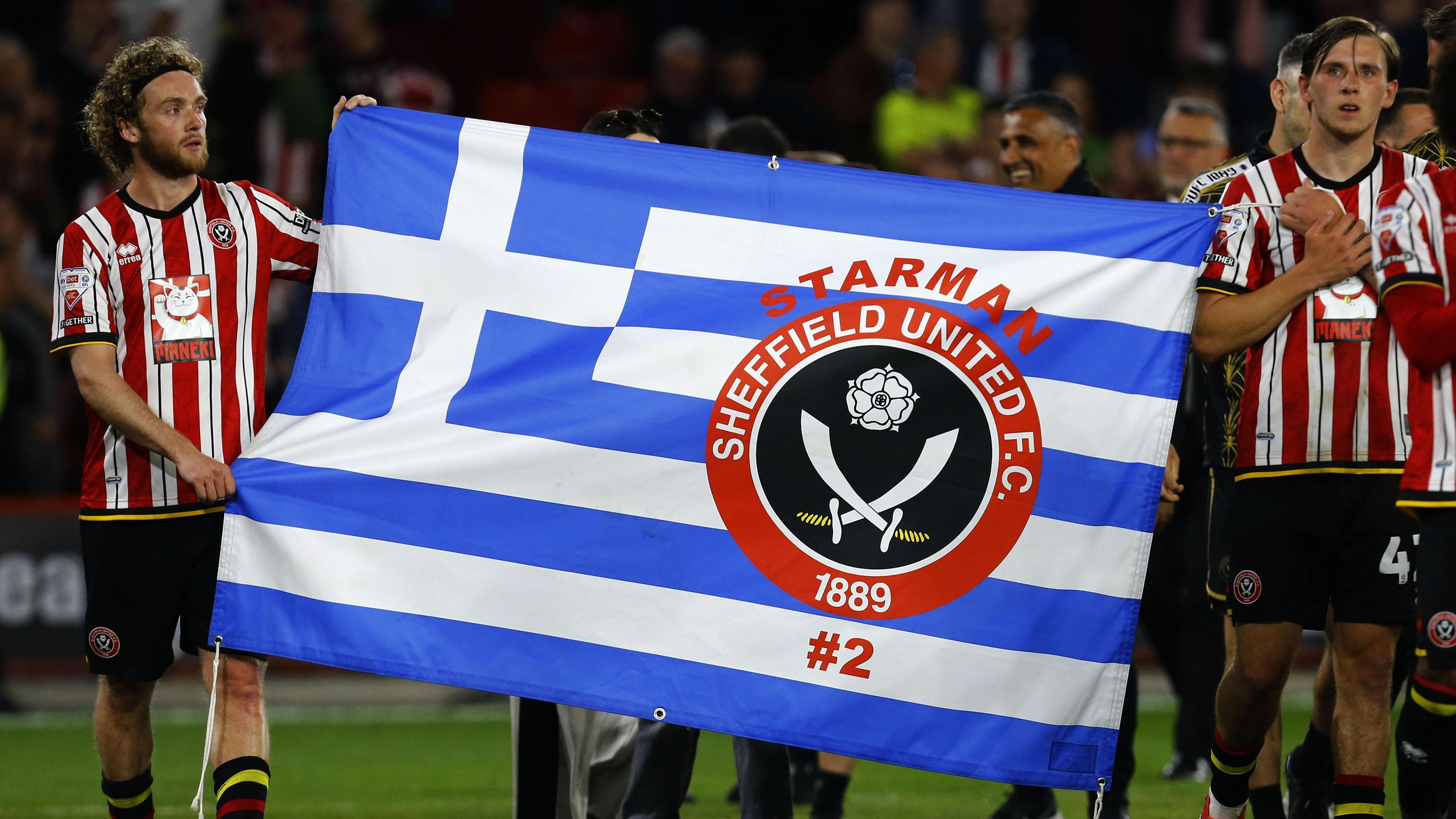 Sheffield United players with a Greece flag with George Baldock's number on it.