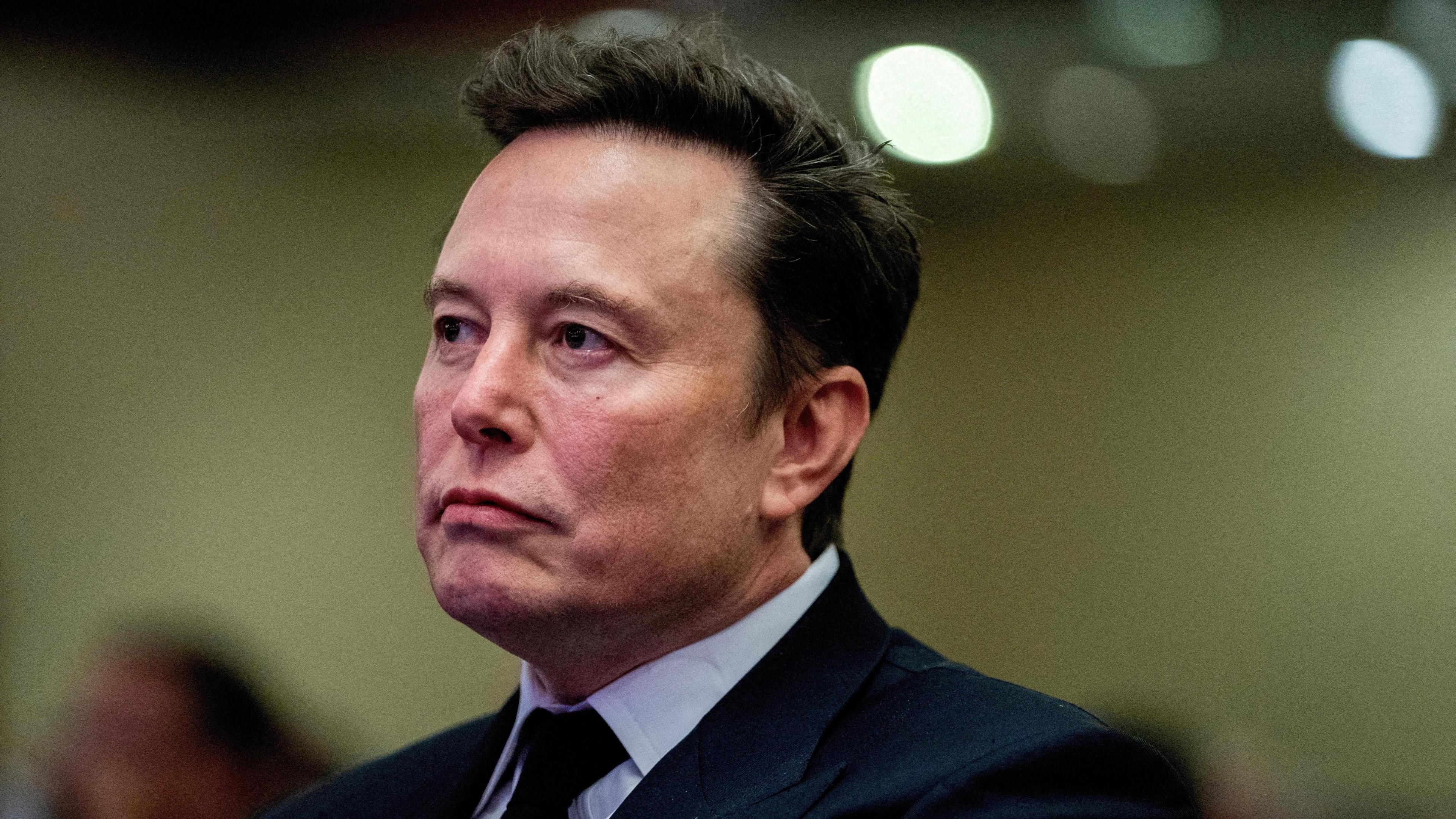 A close-up shot of Tesla CEO and X owner Elon Musk listening as US President-elect Donald Trump speaks to a meeting of House of Representatives Republicans