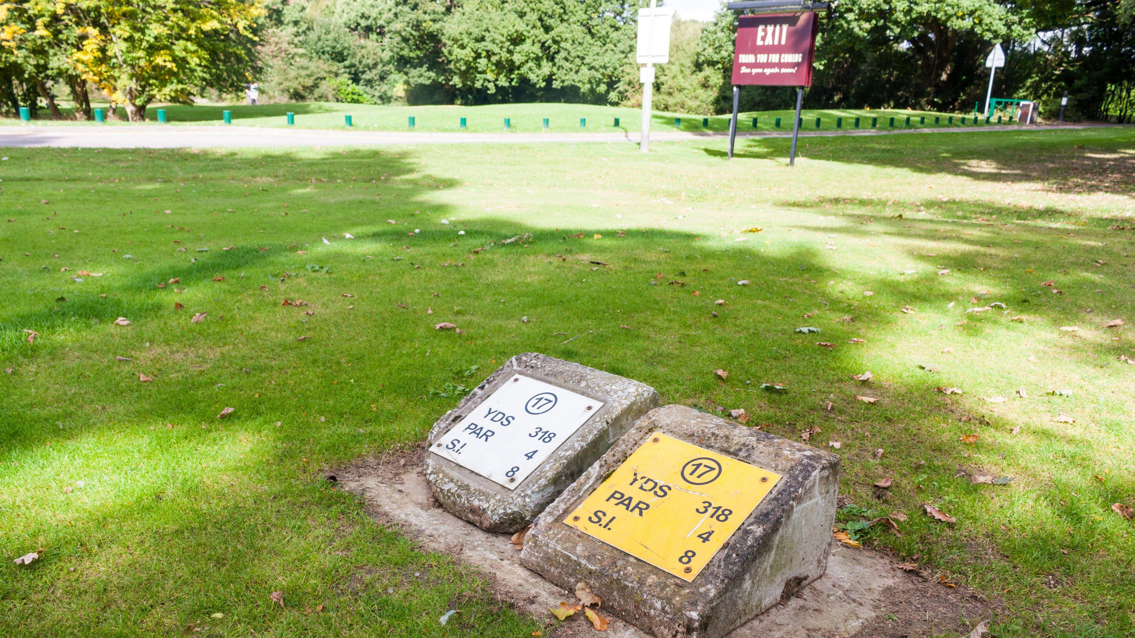 Tee markers denoting the teeing ground for hole 17 at Ruislip Golf Course with green grass behind