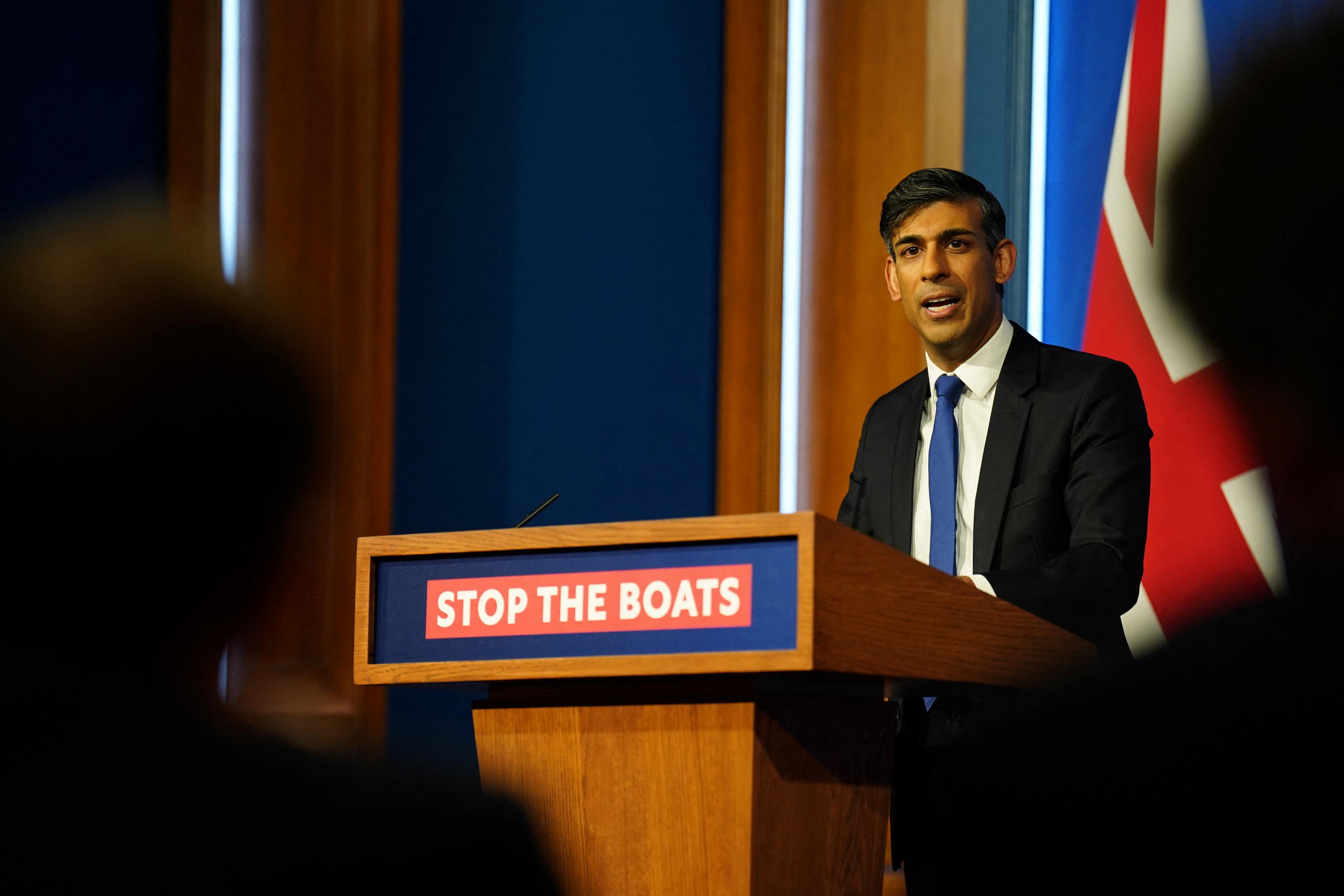 Prime Minister Rishi Sunak standing at a podium that reads "Stop the boats".