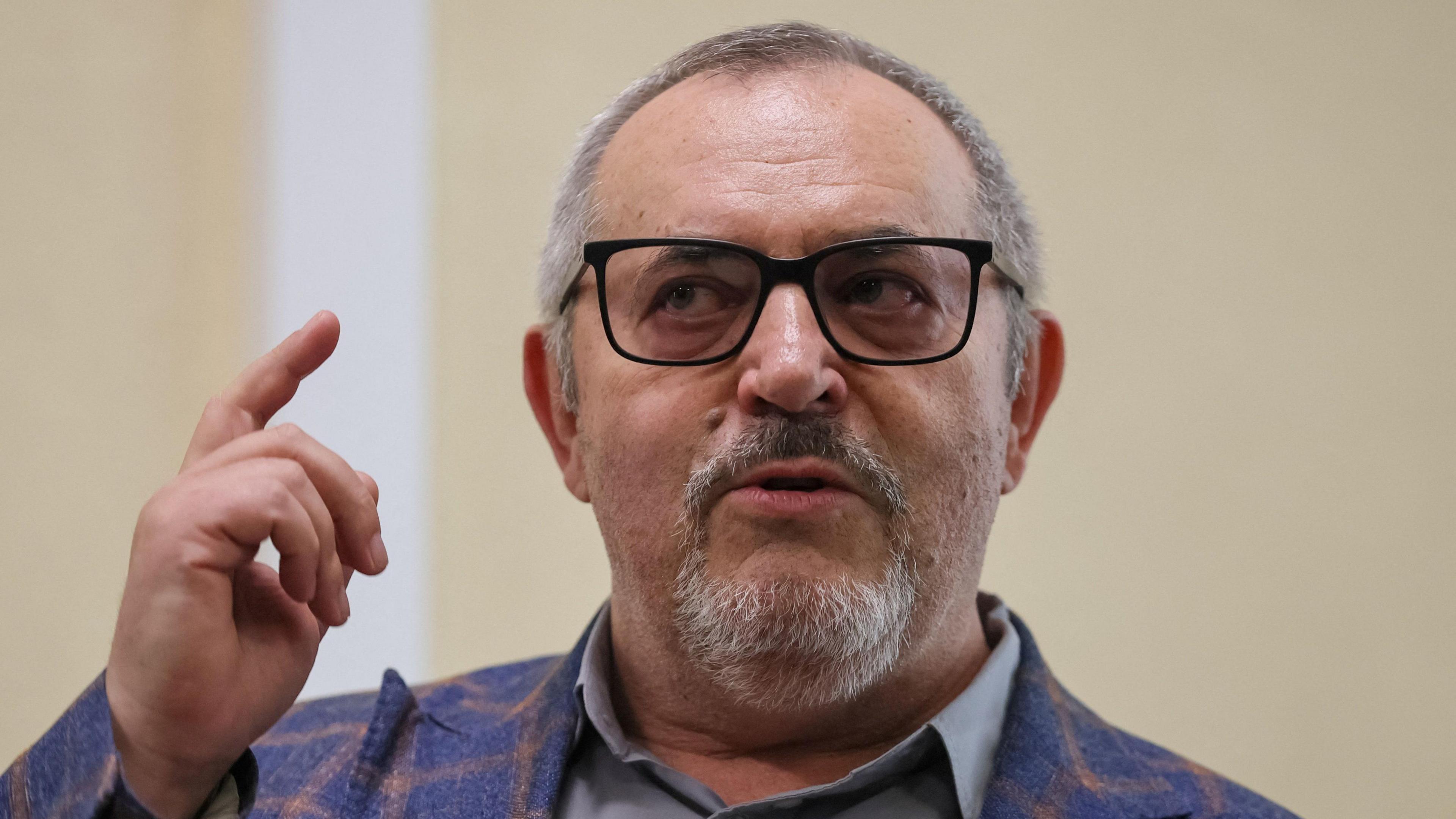Boris Nadezhdin, who has short grey hair, wears a colourful blazer and glasses in court in Dolgoprudny, Moscow region, last month. He is pointing upwards with his right index finger.