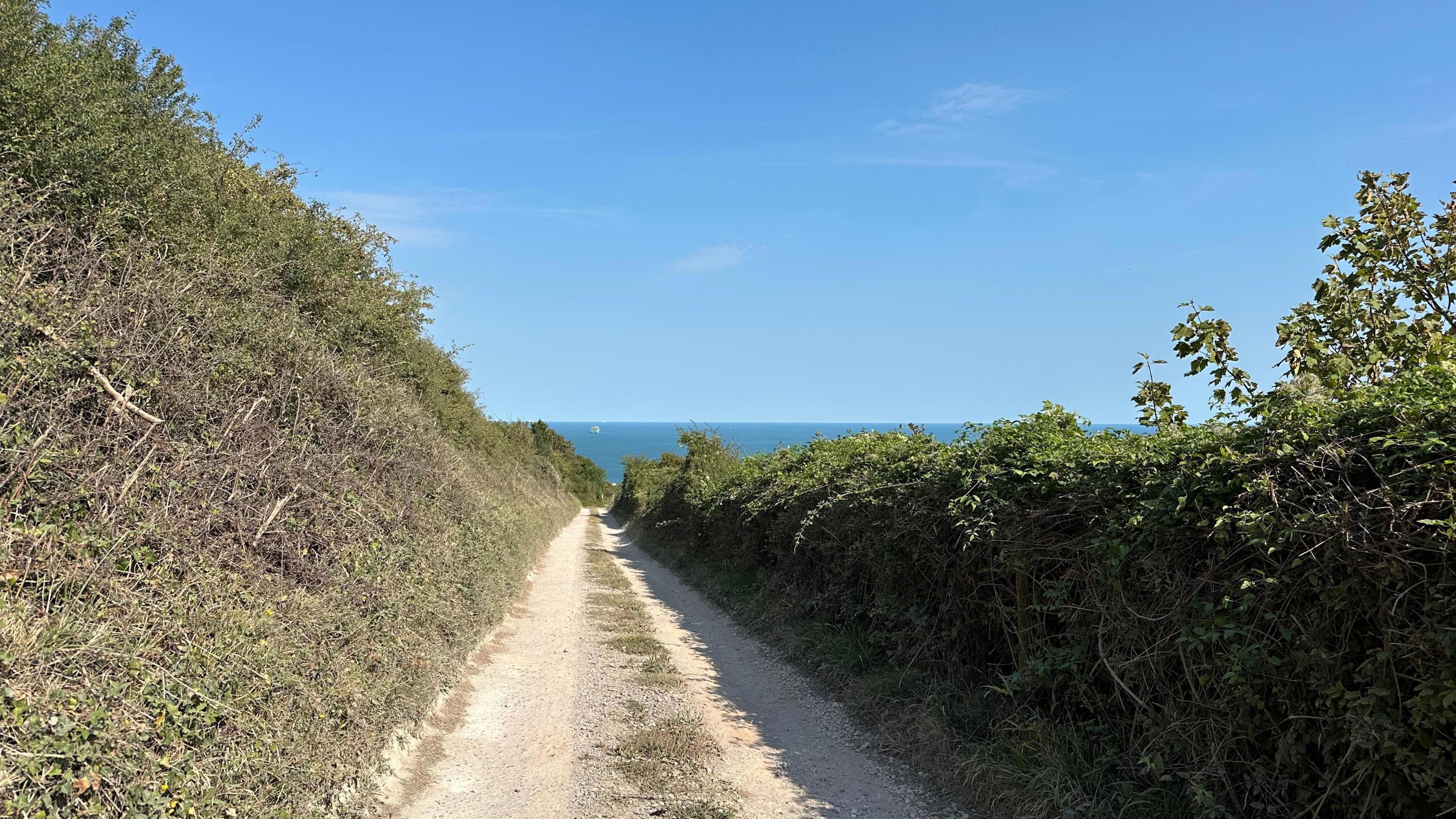 An empty footpath overlooking the sea and under the sunshine