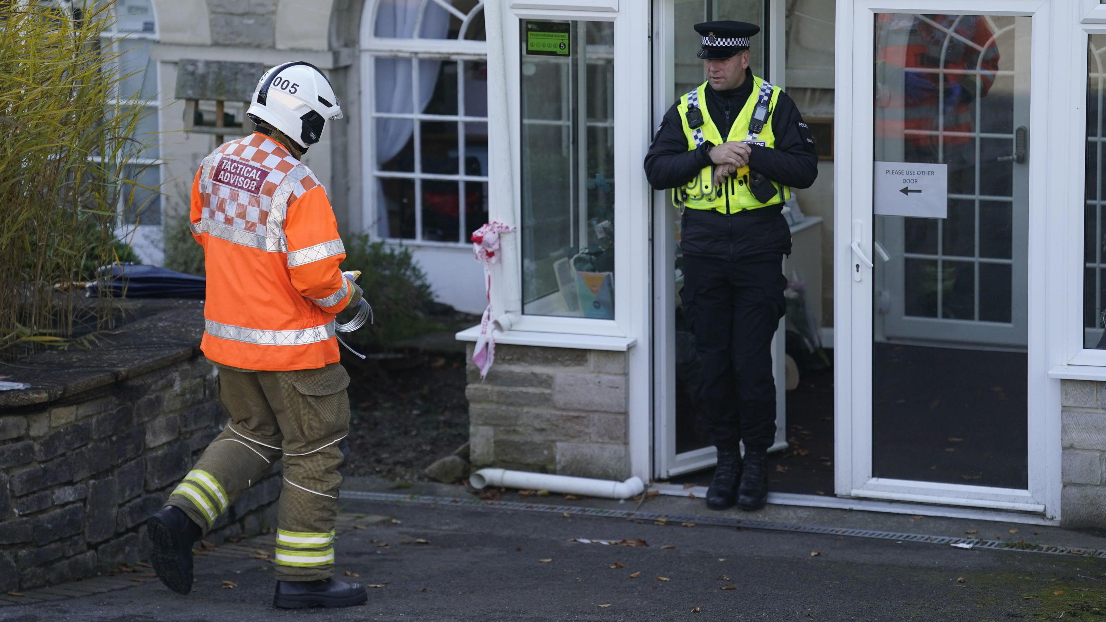 A helmeted firefighter and a policeman greet each other at the doorway of Gainsborough Care Home