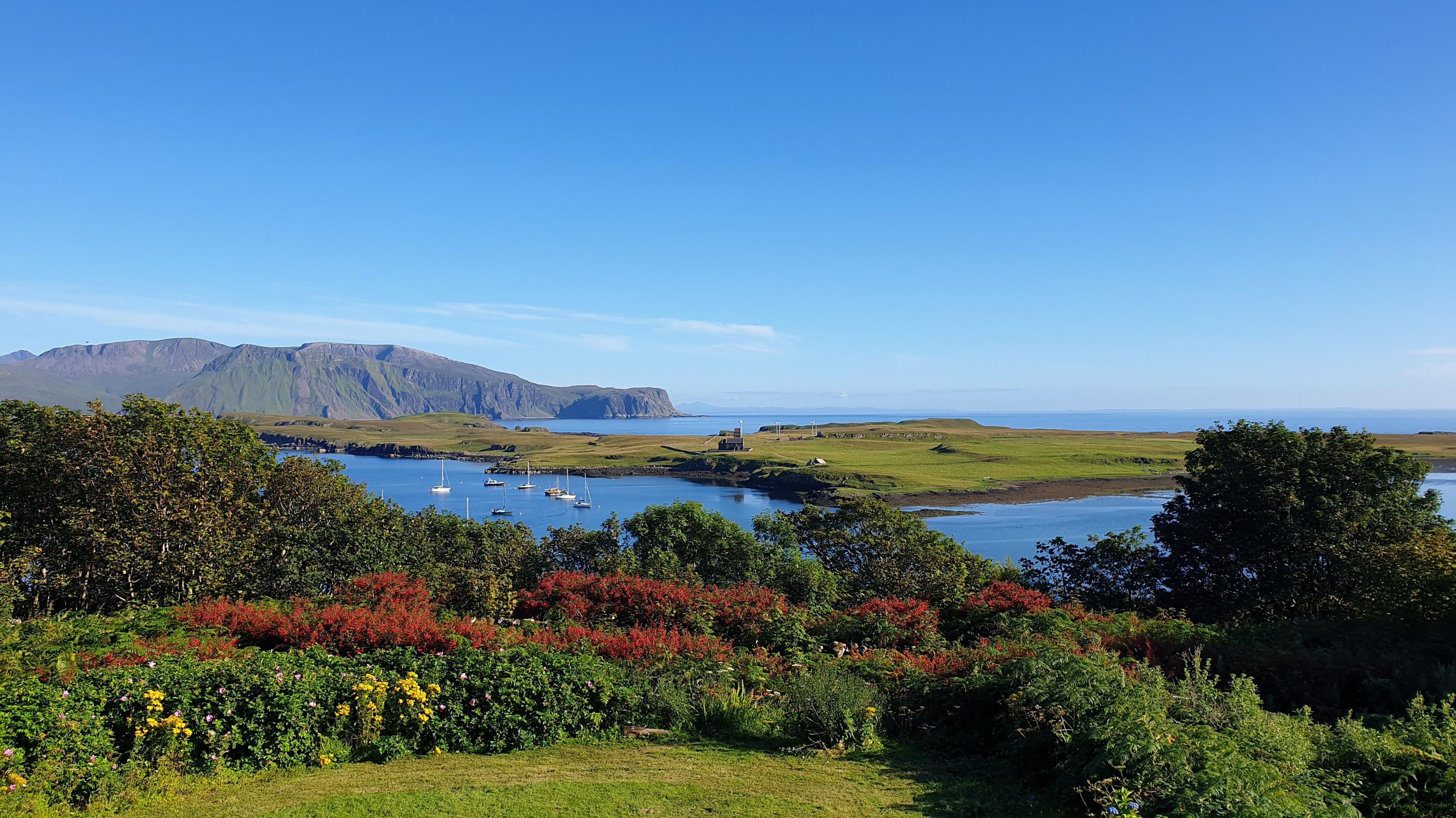 Landscape image of the Isle of Canna on a sunny day with clear blue skies,  looking out to the sea