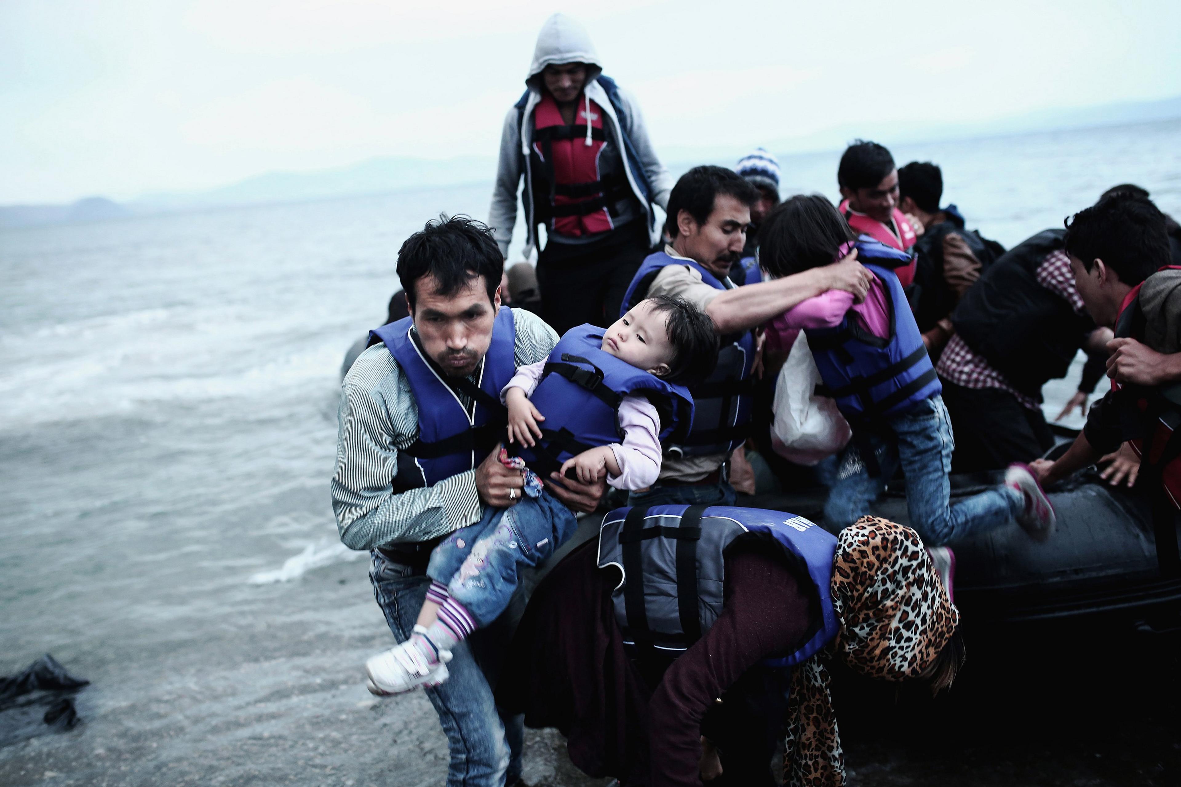 An Afghan refugee carries his child as he arrives on a beach on the Greek island of Kos, after crossing a part of the Aegean Sea between Turkey and Greece