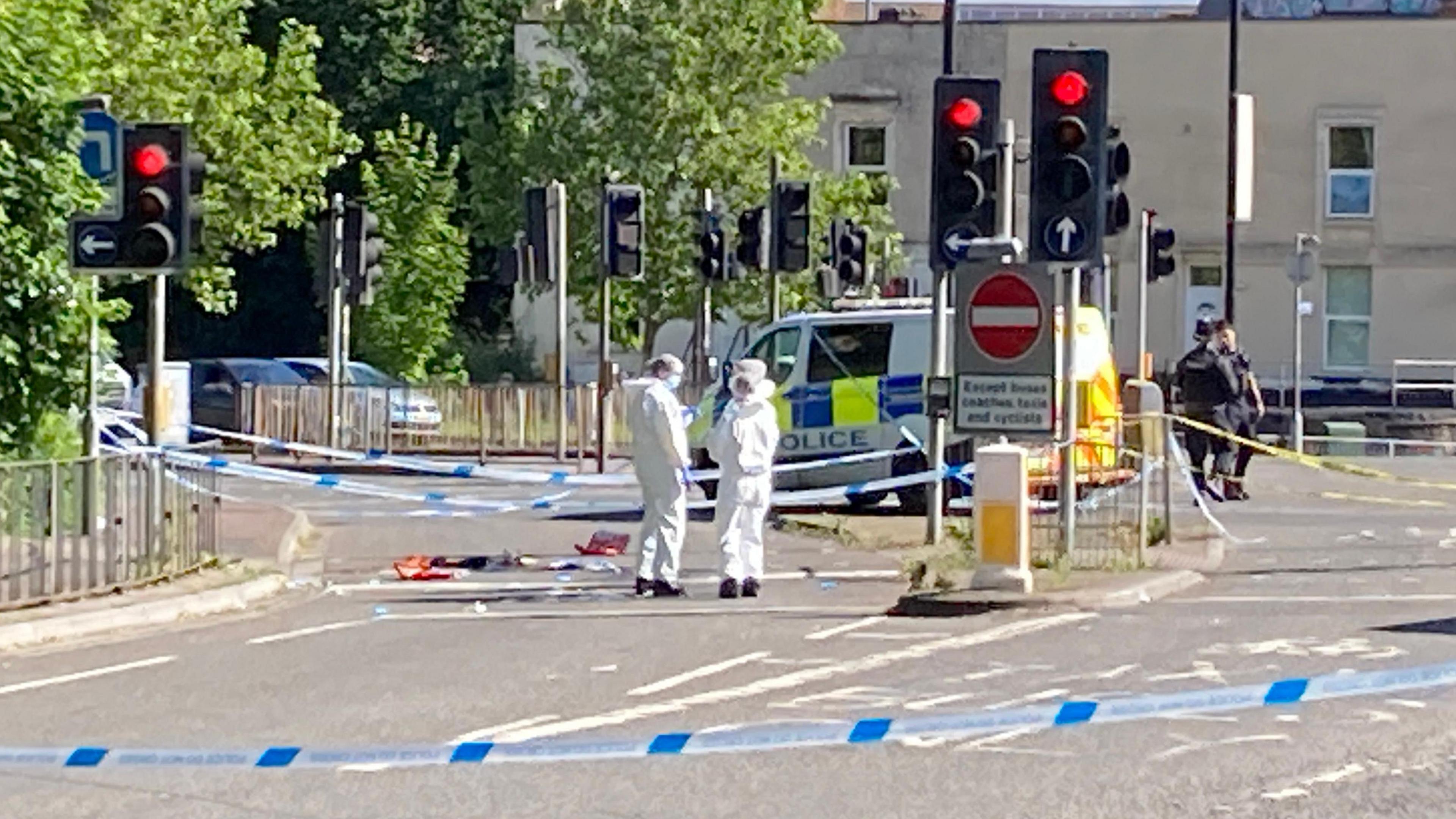 Forensics behind a police cordon next to some traffic lights