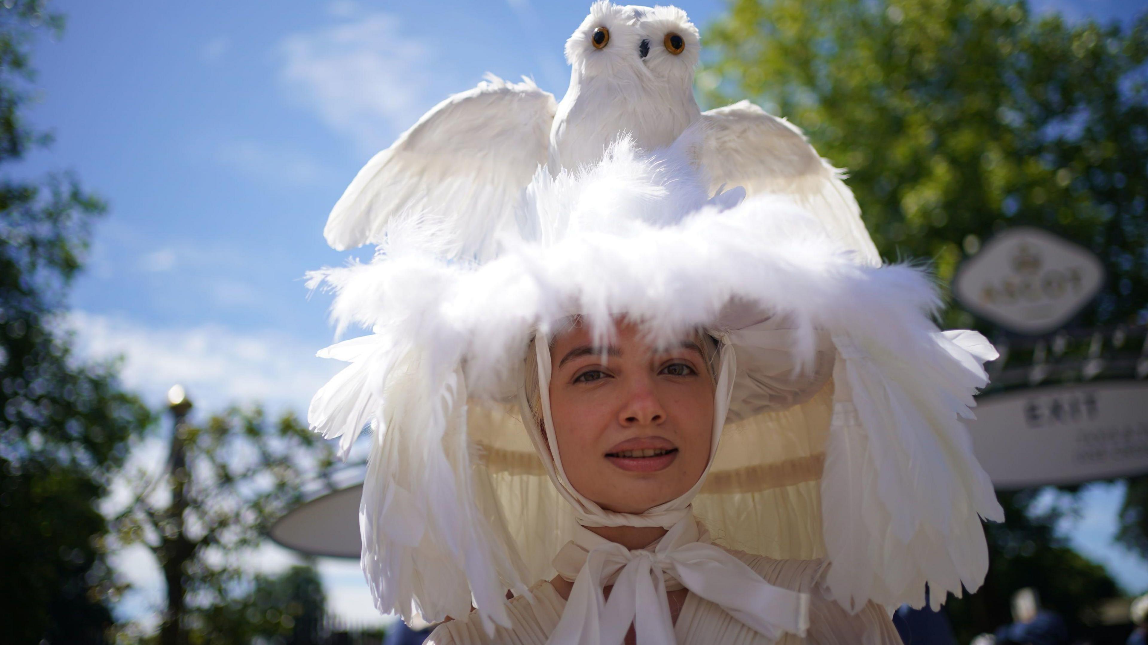 Angelina Chebotareva Rockefeller wears a large white hat covered in feathers with an owl on top