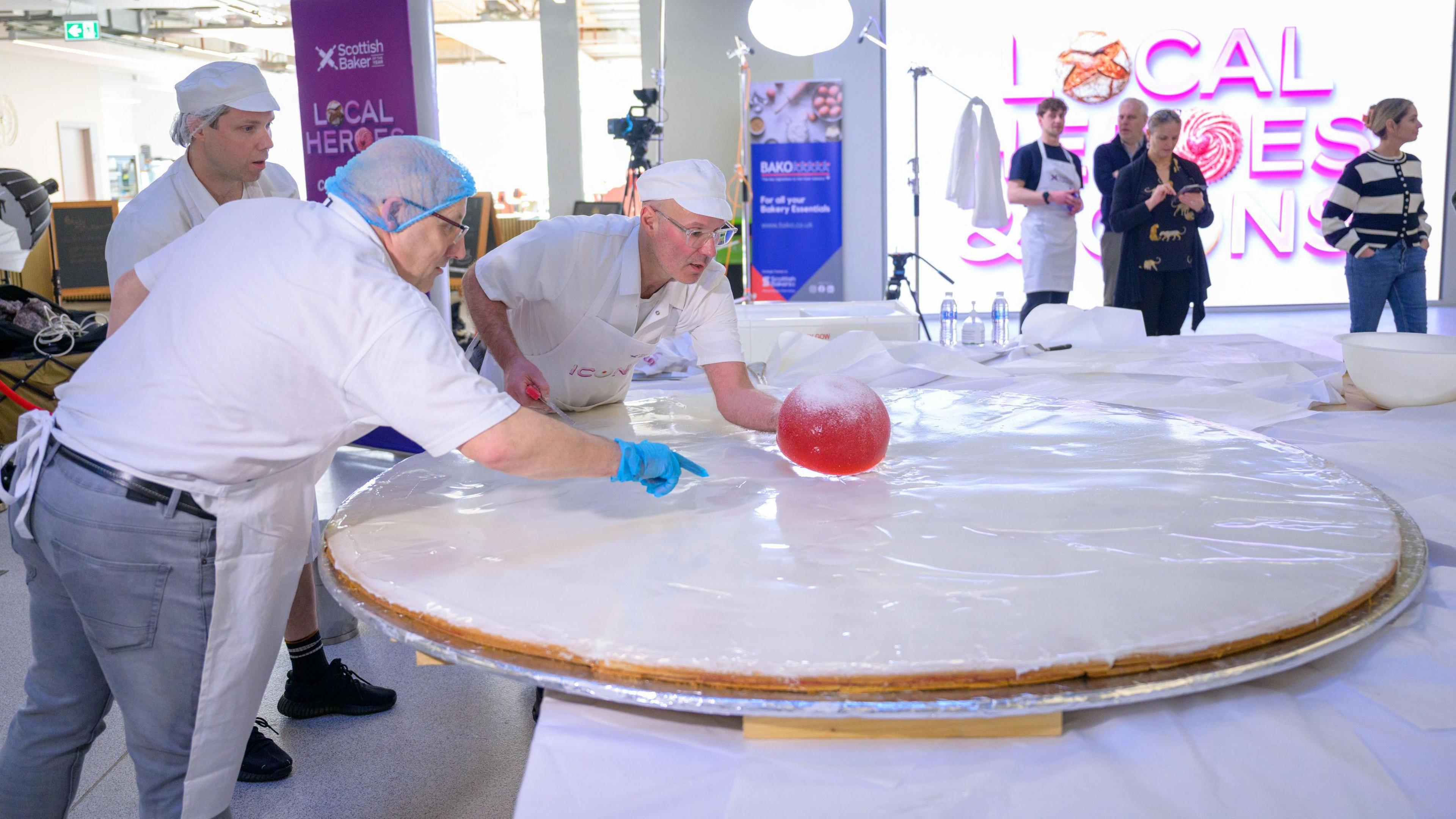 bakers putting the giant jelly sweet on top of their jumbo biscuit