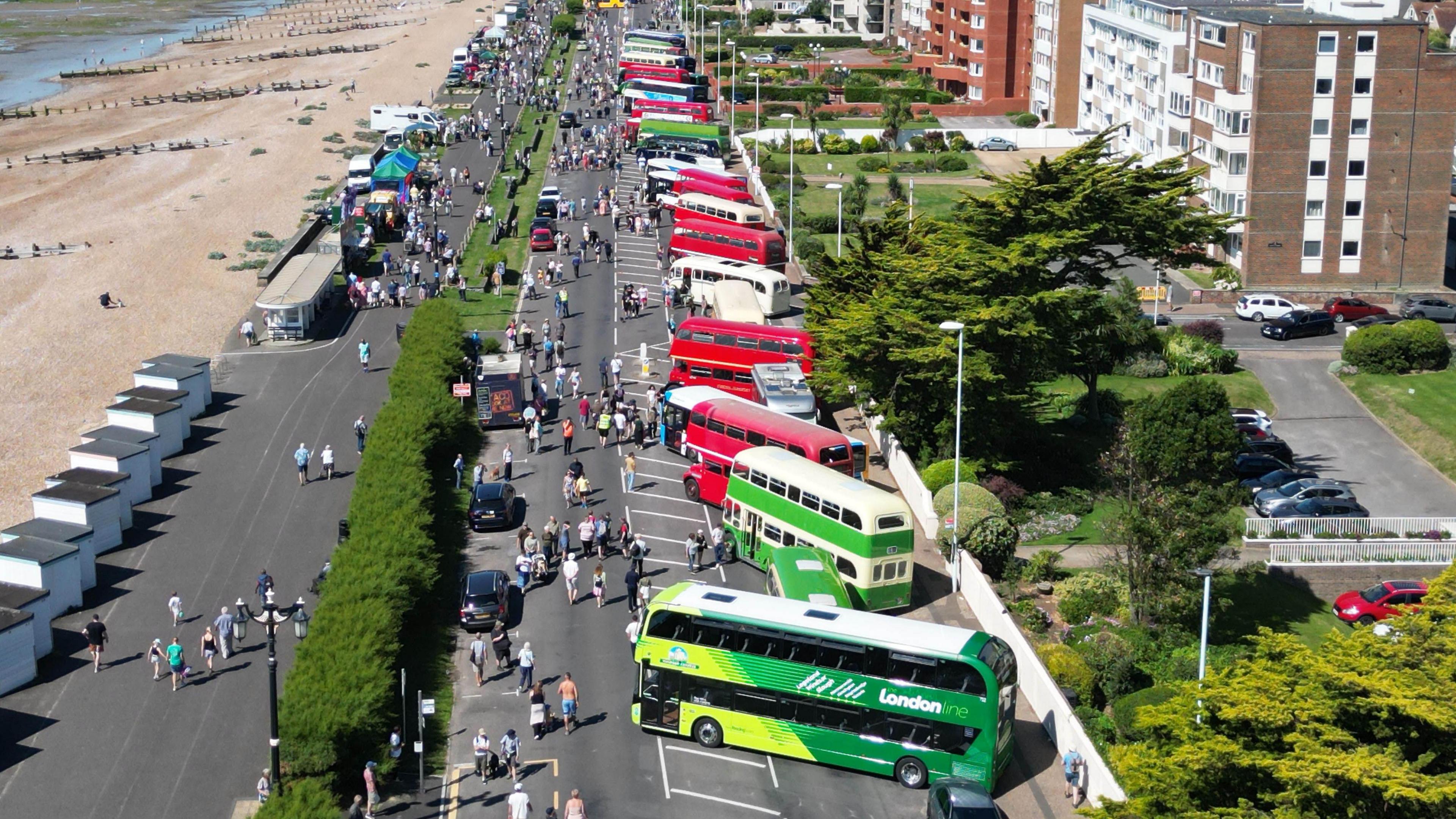 Aerial shot of Worthing Bus Rally 2024 showing buses of various ages parked up on the seafront with crowds looking at them