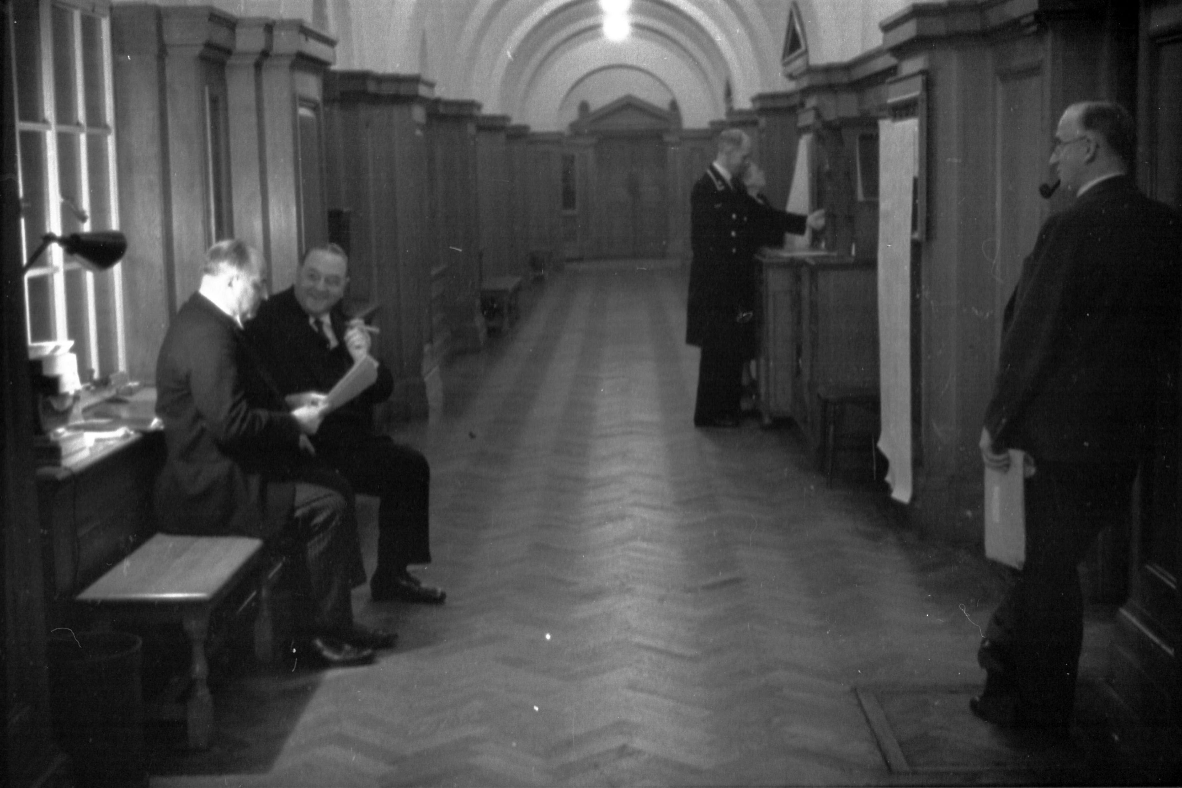 Black and white image of four men wearing suits in a corridor in London Country Hall in 1938