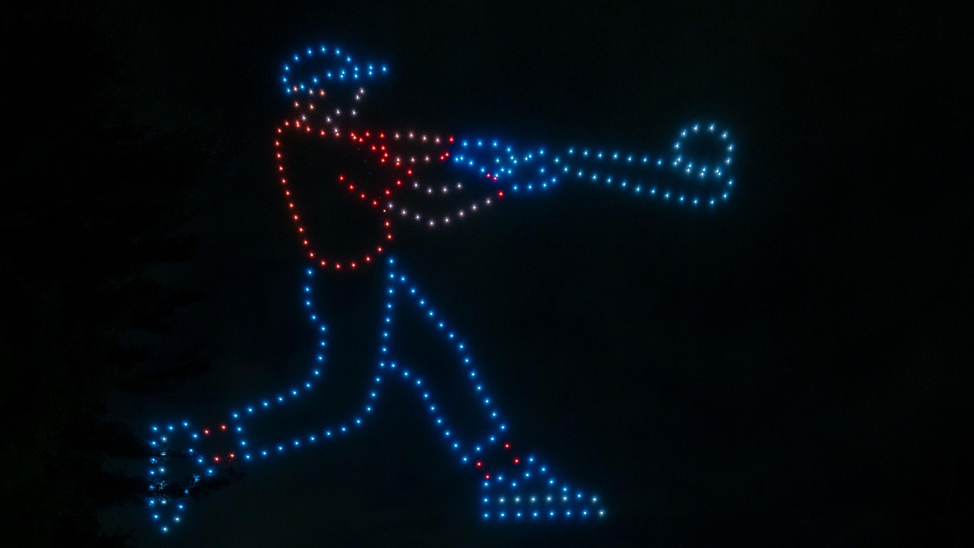 An outline of a baseball player hitting a ball, made be drones