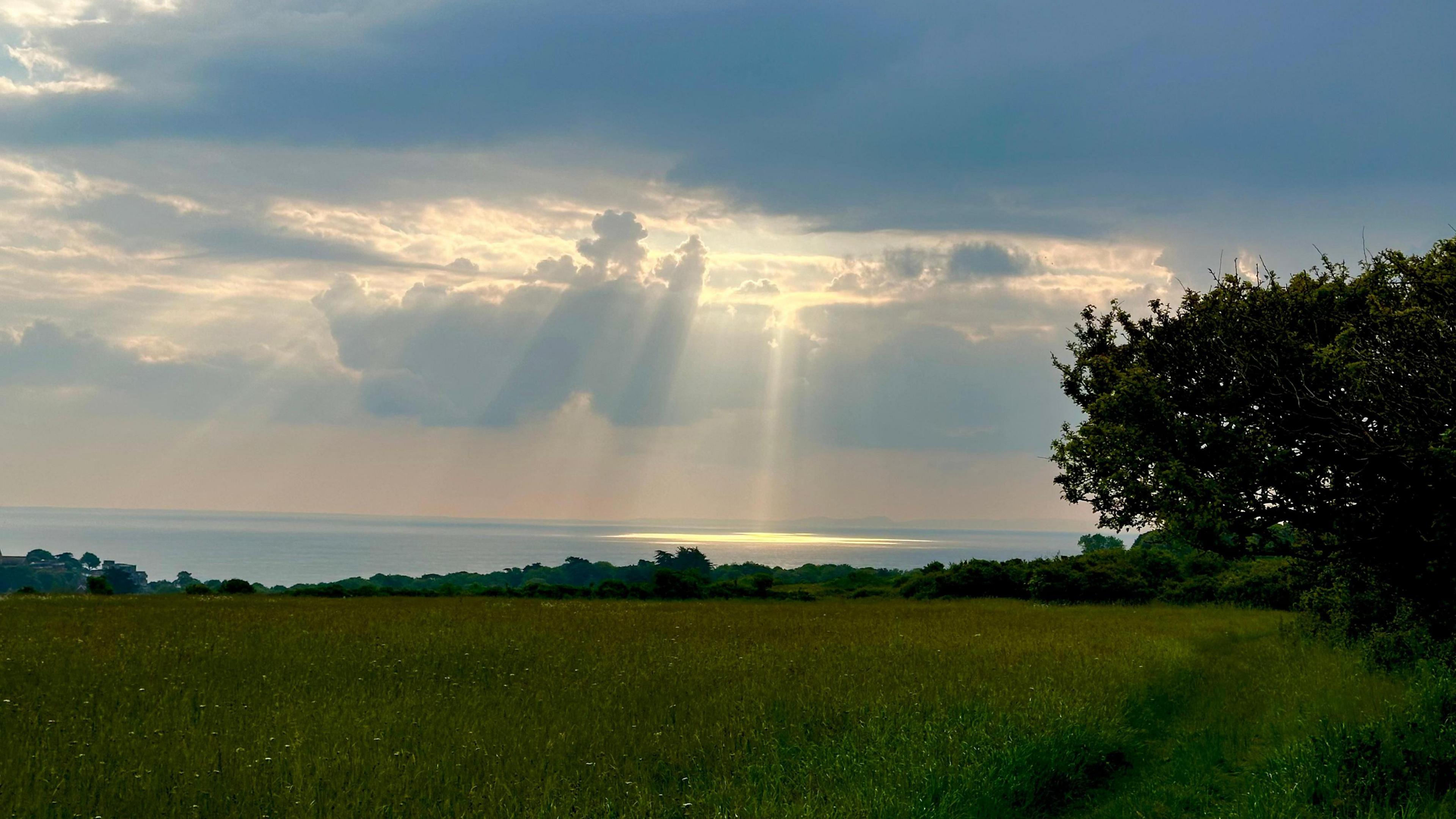 FRIDAY - The sun streaming through the clouds over the coast off Swanage