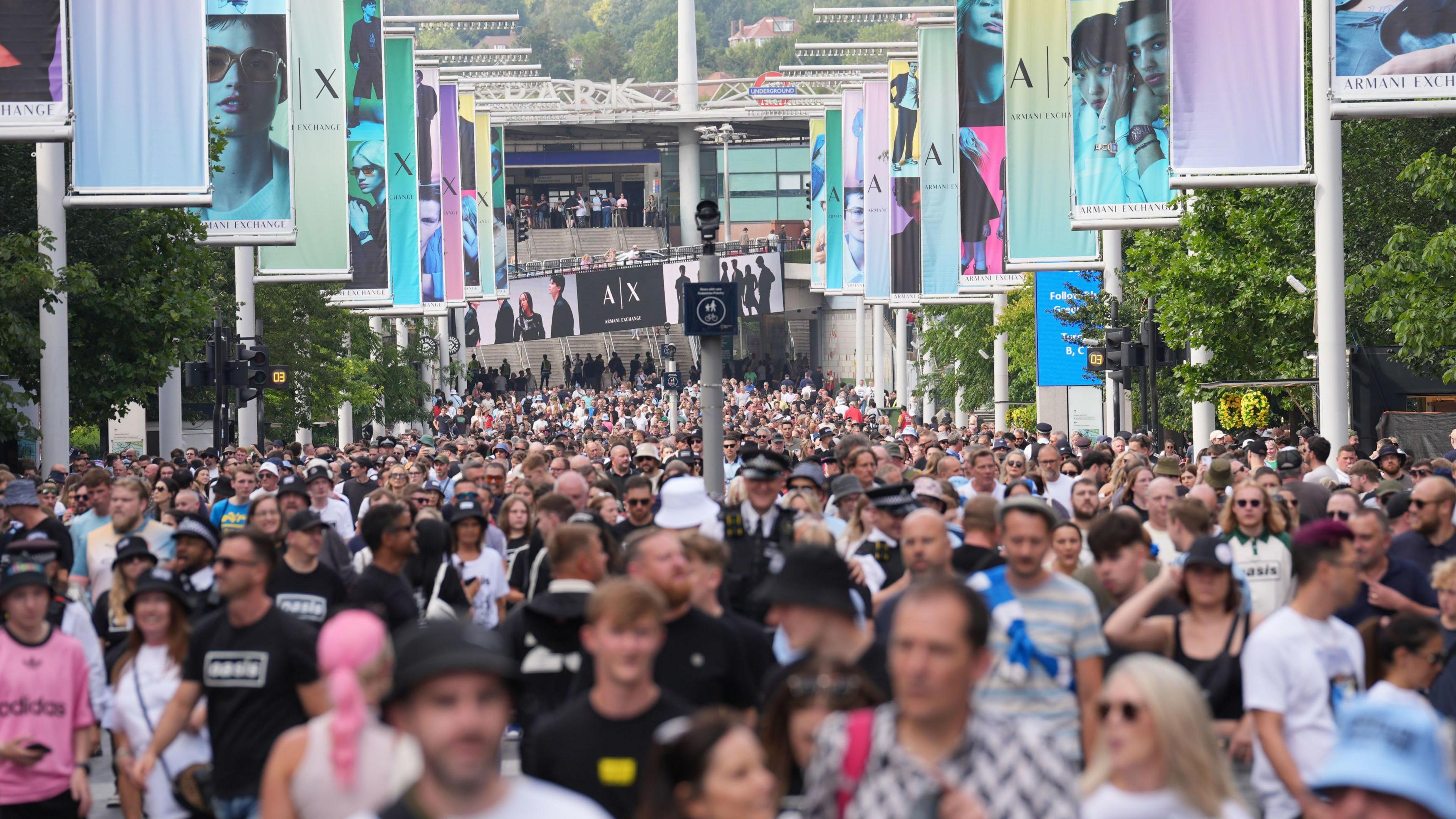 Oasis fans, some wearing t-shirts featuring the band's name, on Wembley Way.