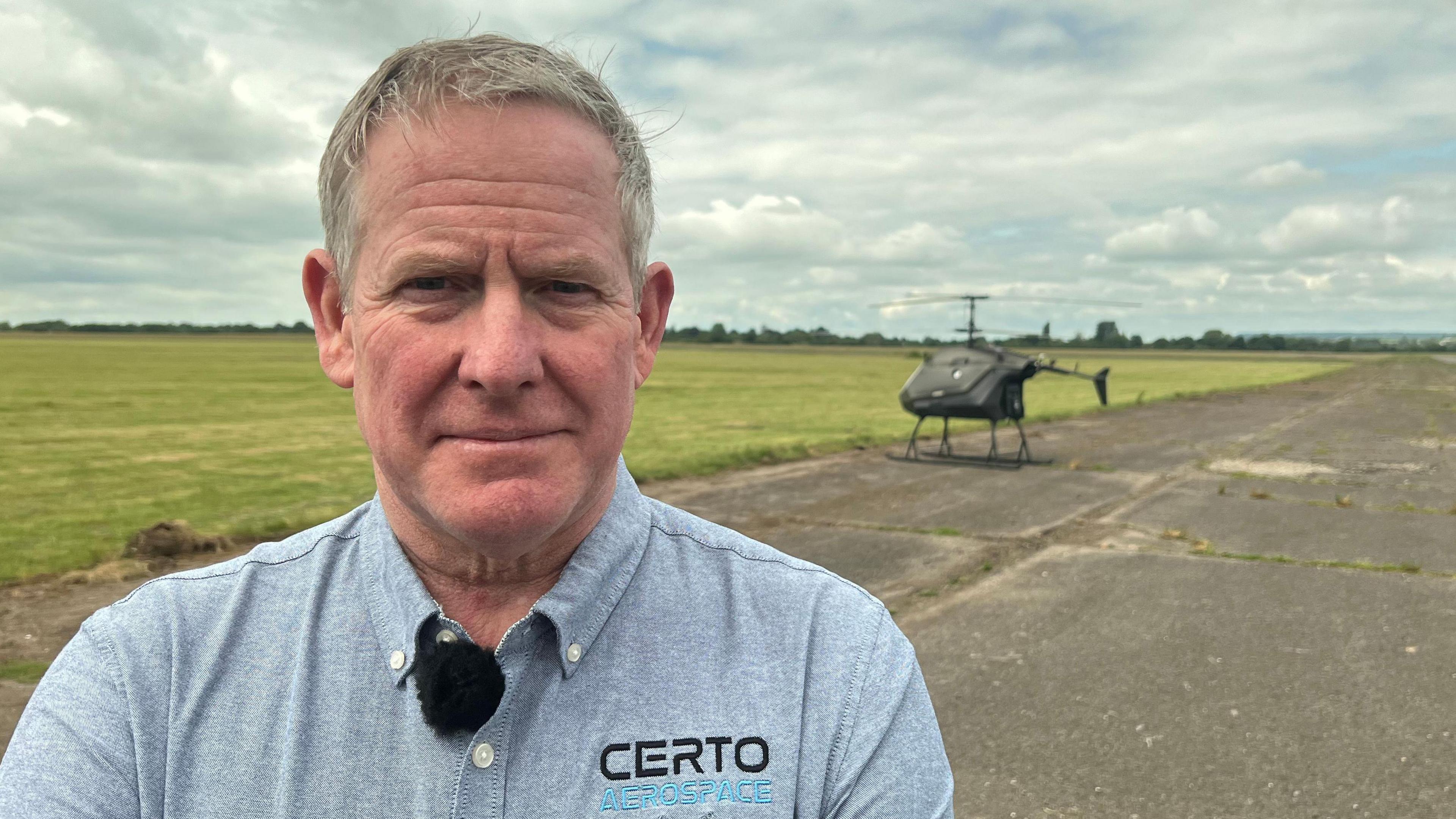 The CEO of a helicopter manufacturer stands in front of his unmanned helicopter at Keevil Airfield.
