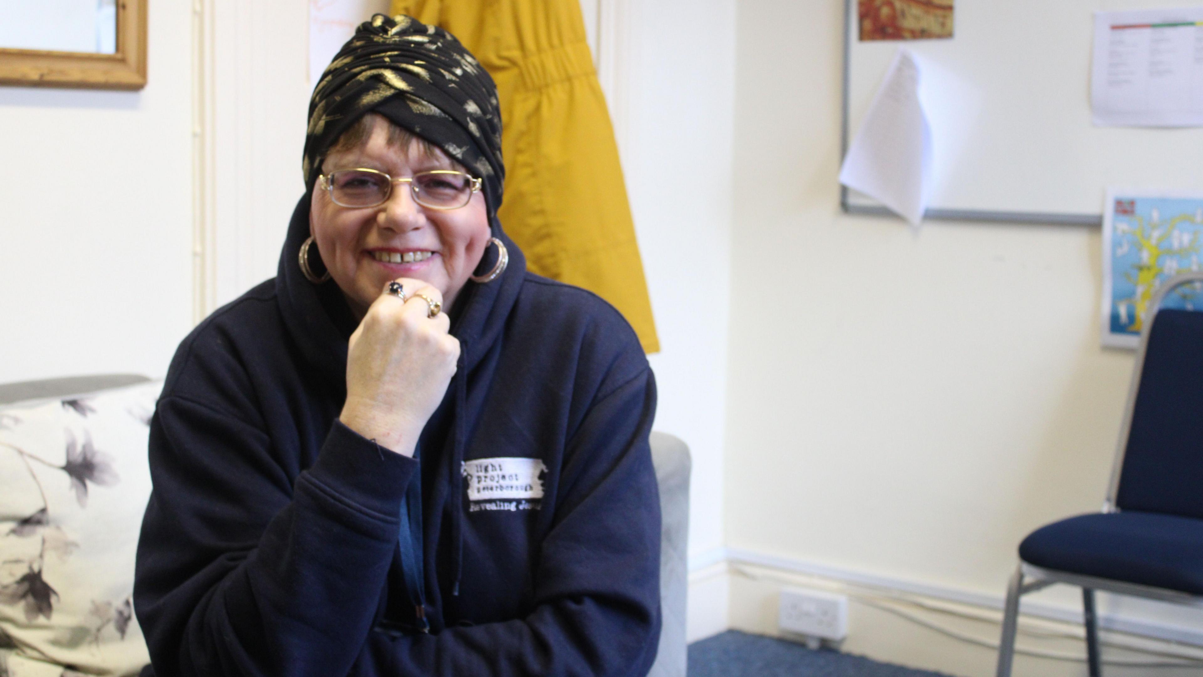 Davina wearing a blue fleece and a black and yellow head scarf