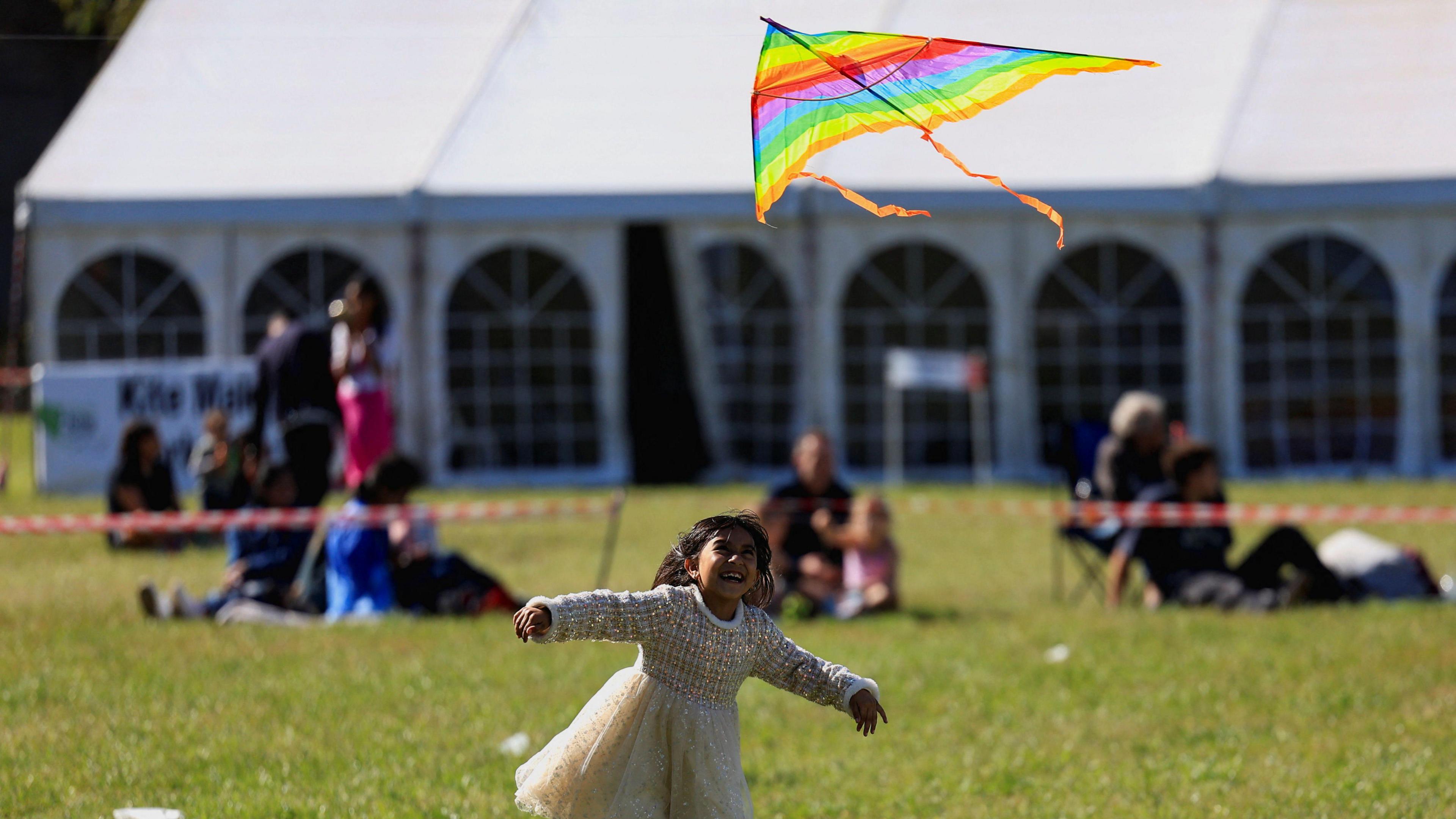 Young girl seen playing with a small striped kite