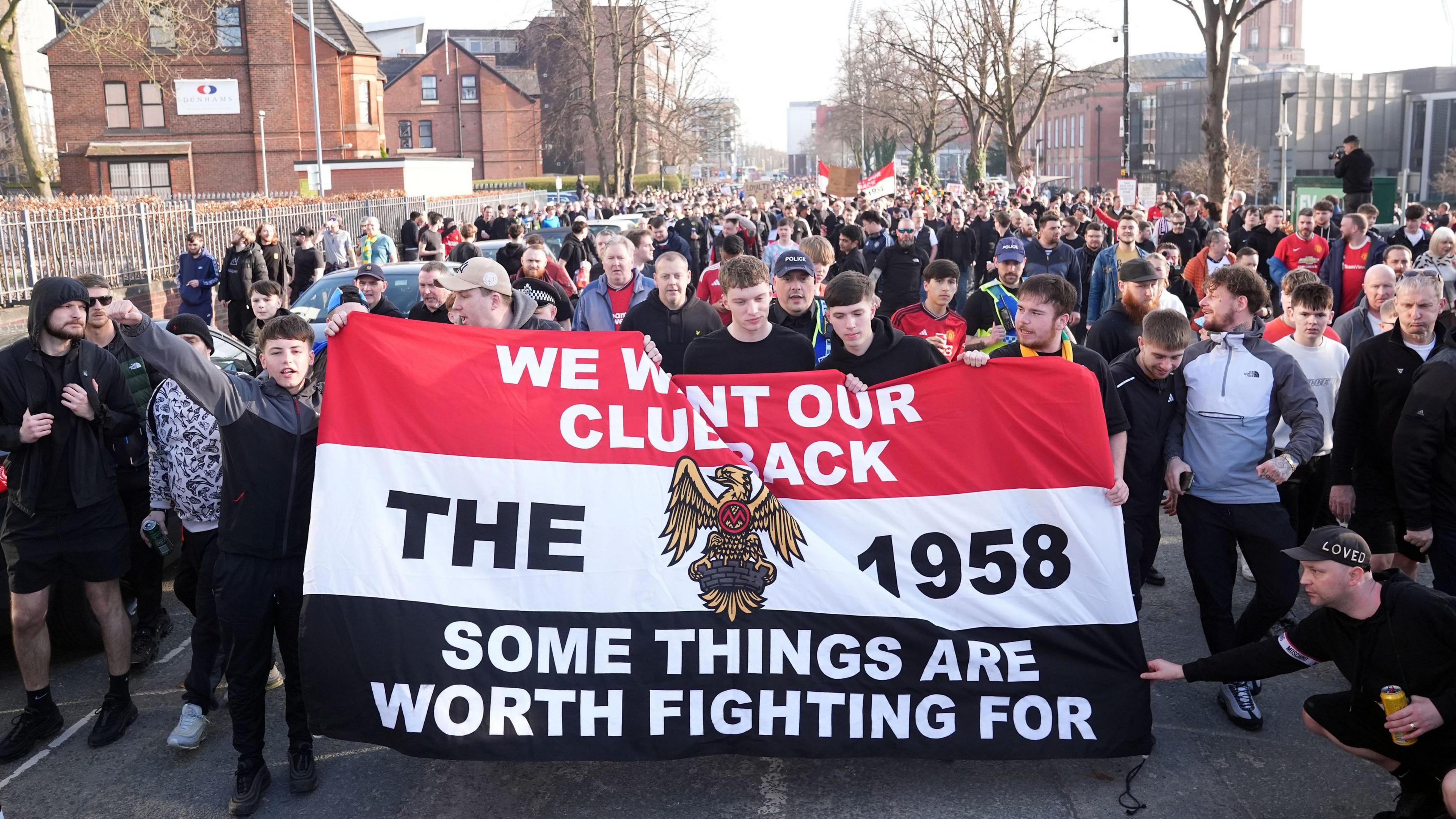  Manchester United fans protesting holding a banner reading 'we want our club back. the 1958. some things are worth fighting for'