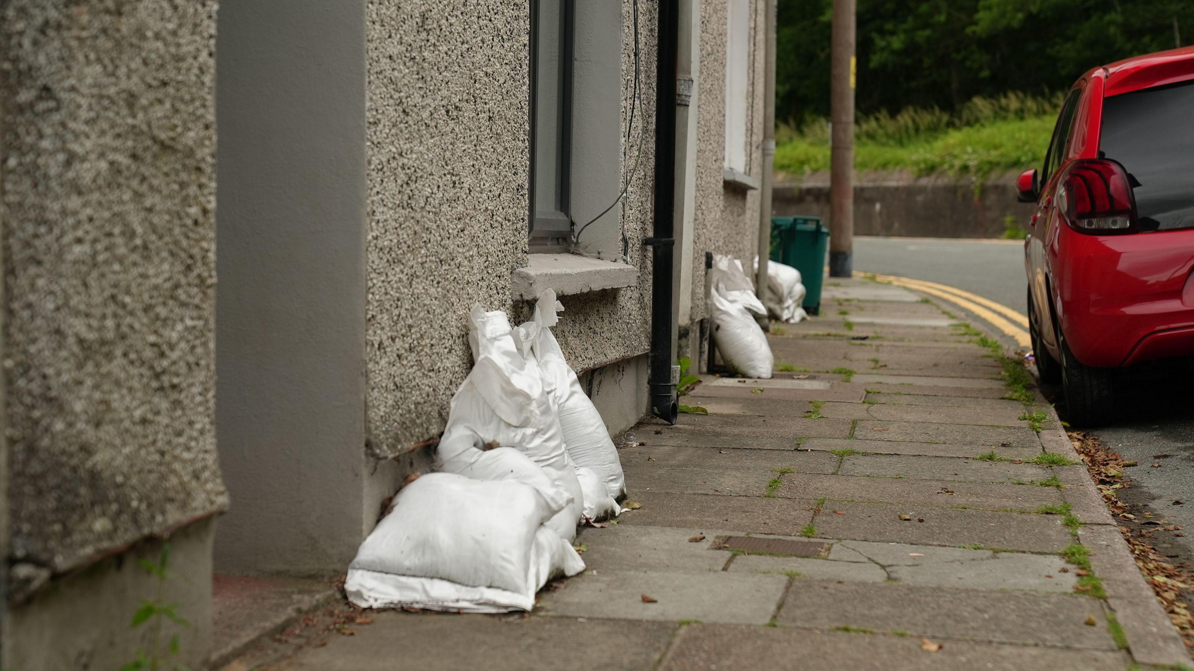 Bagiau tywod y tu allan i gartrefi yn Clydach Terrace, Ynysybwl