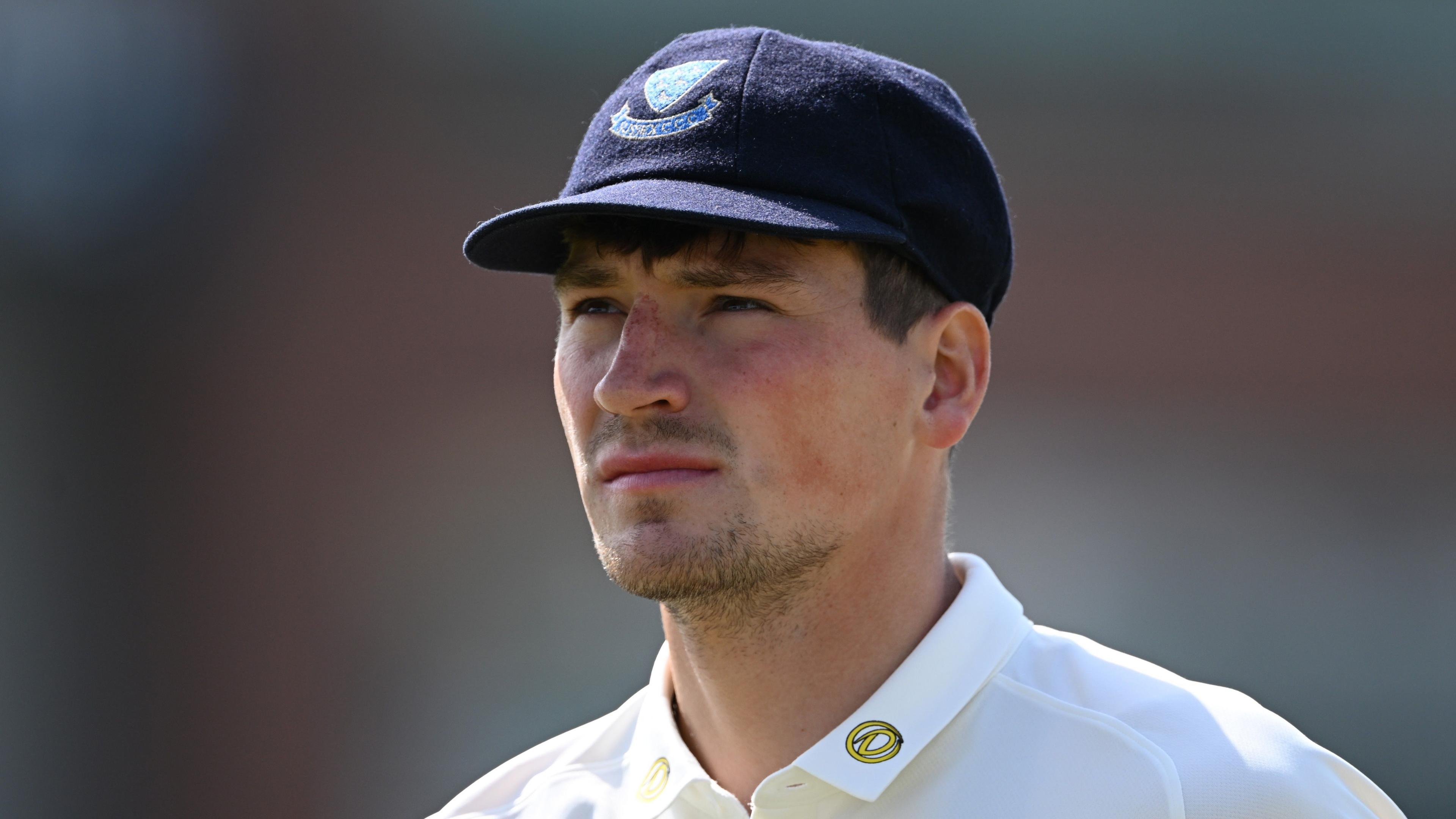 Henry Crocombe looks on, while wearing a blue cap