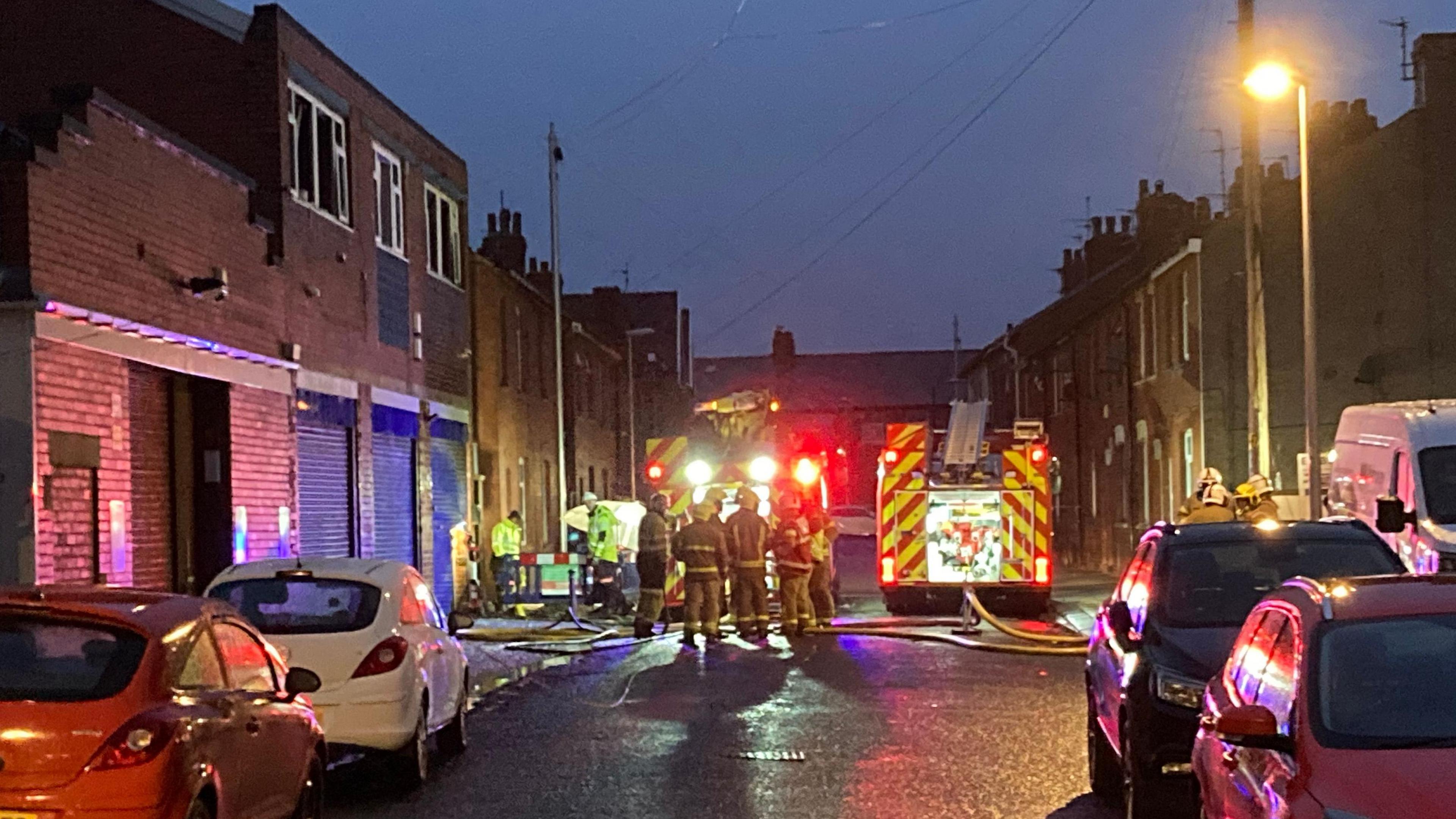Fire crews standing by two fire engines as they tackle a fire at a commercial building.