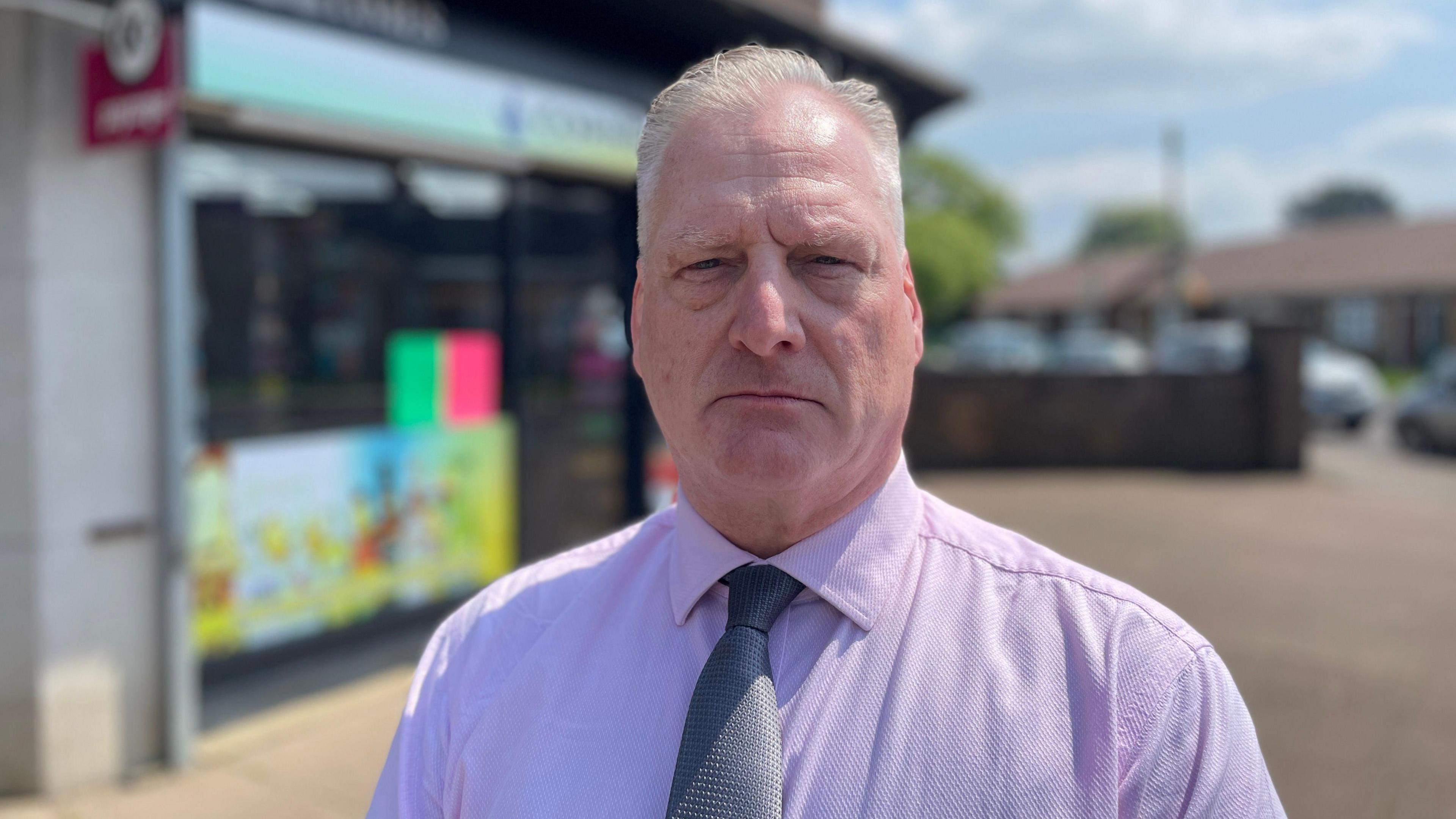 Carl Foster in a shirt and tie stood outside the shop where Carol Morgan was murdered