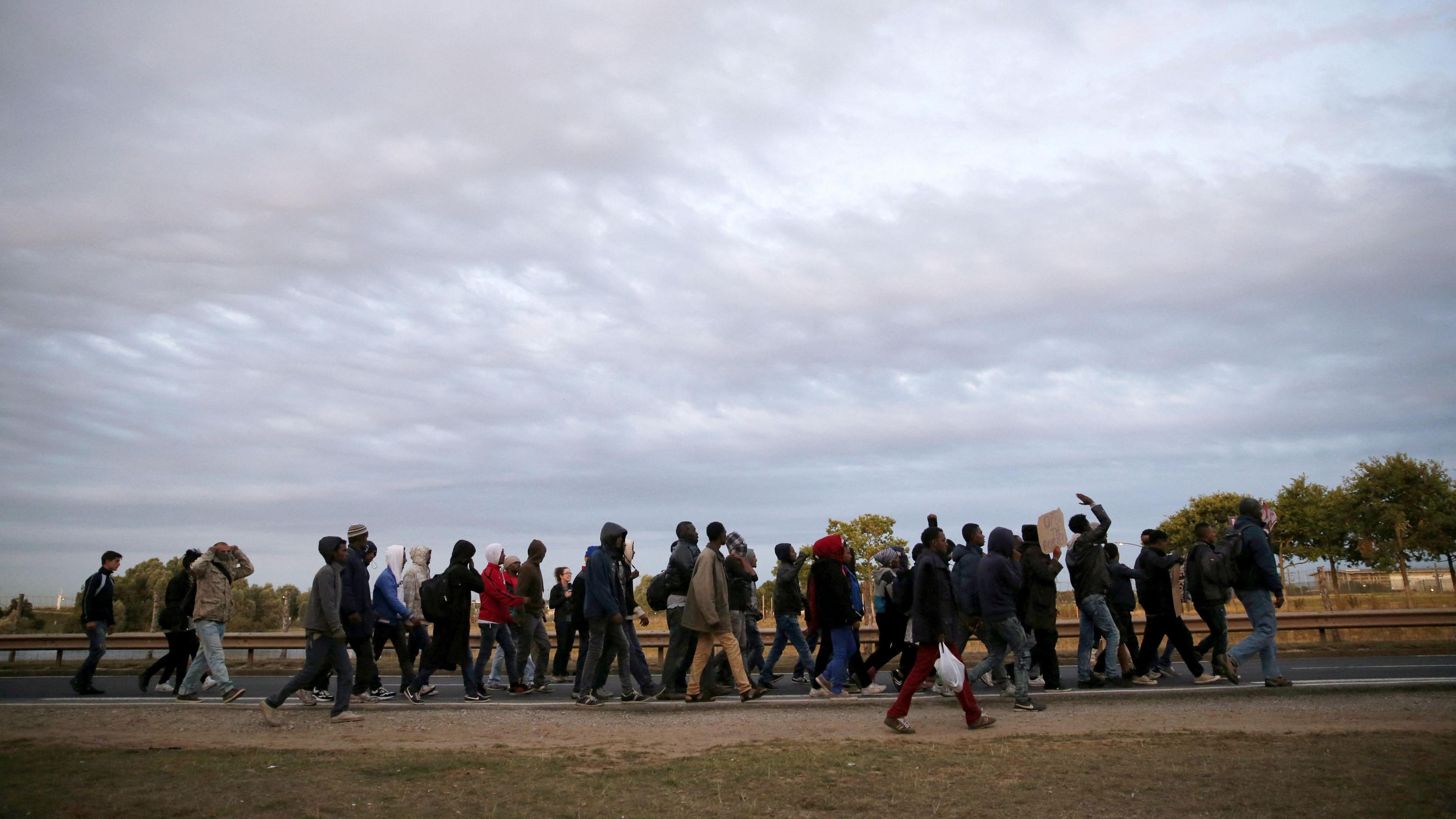 A large group of migrants walking along a motorway in Calais, France