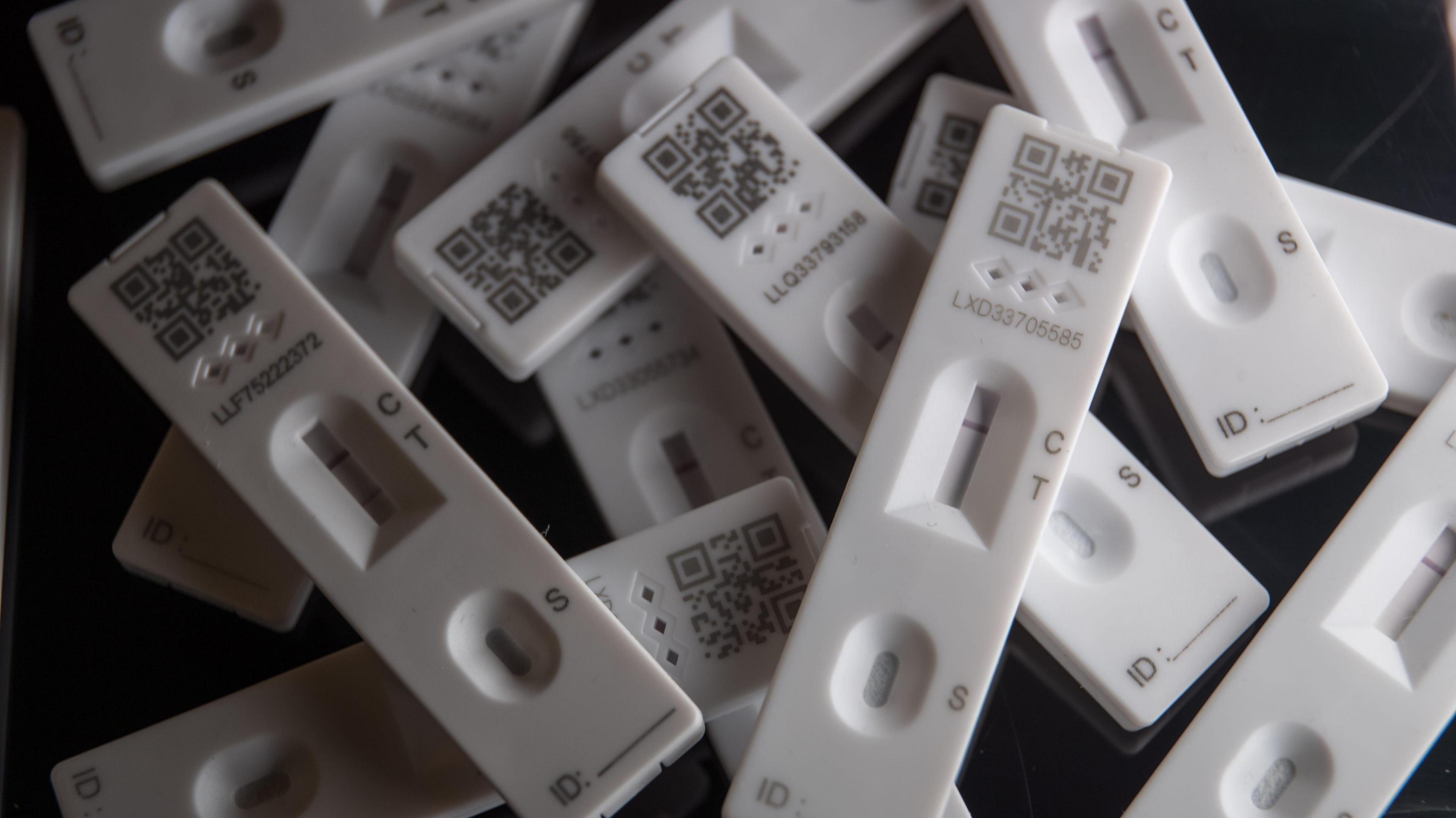 A small pile of Covid tests, stacked in haphazard fashion.