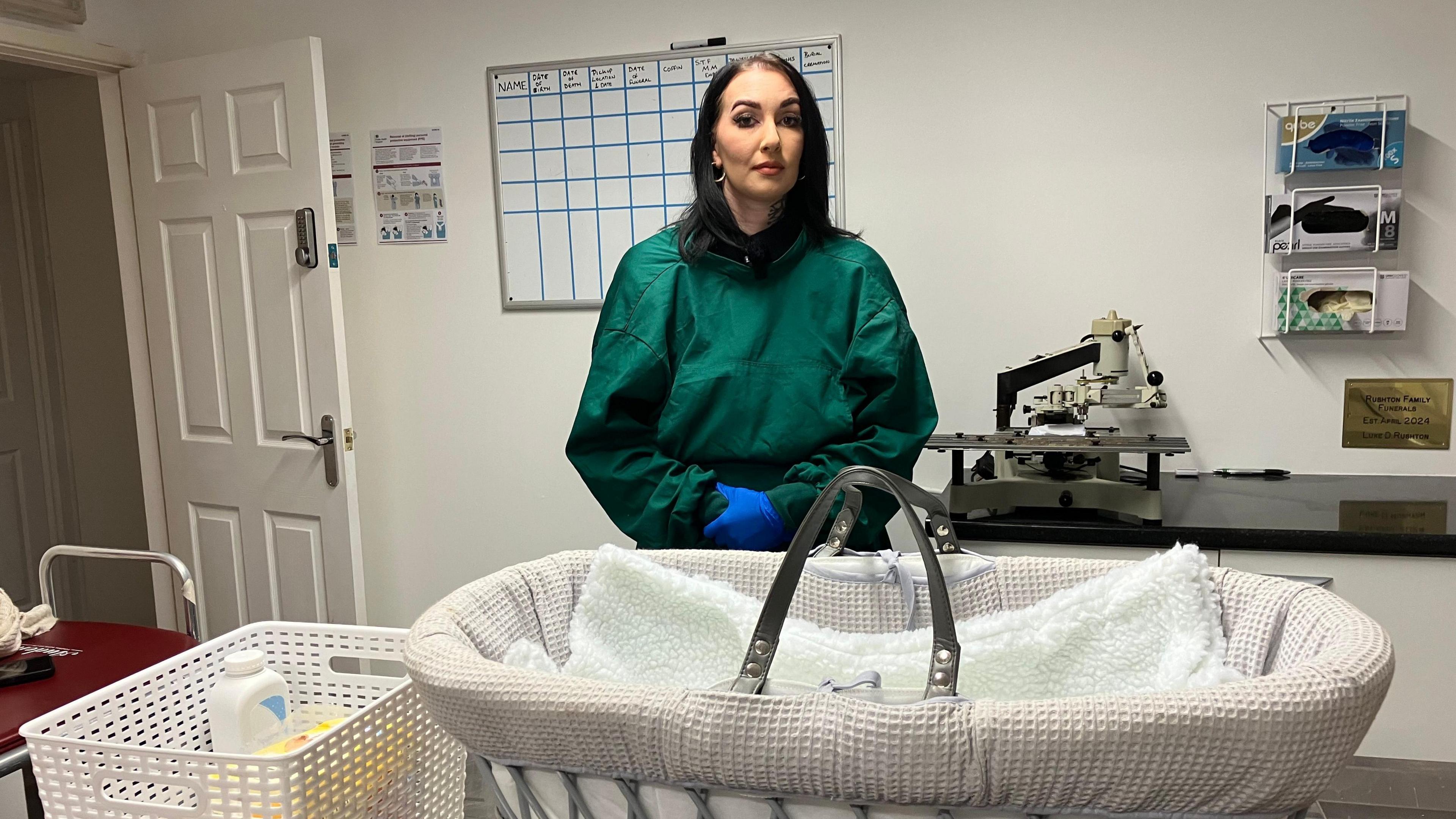 Evie Mawdsley in the mortuary at Rushton Family Funerals. In front of her is a Moses basket.