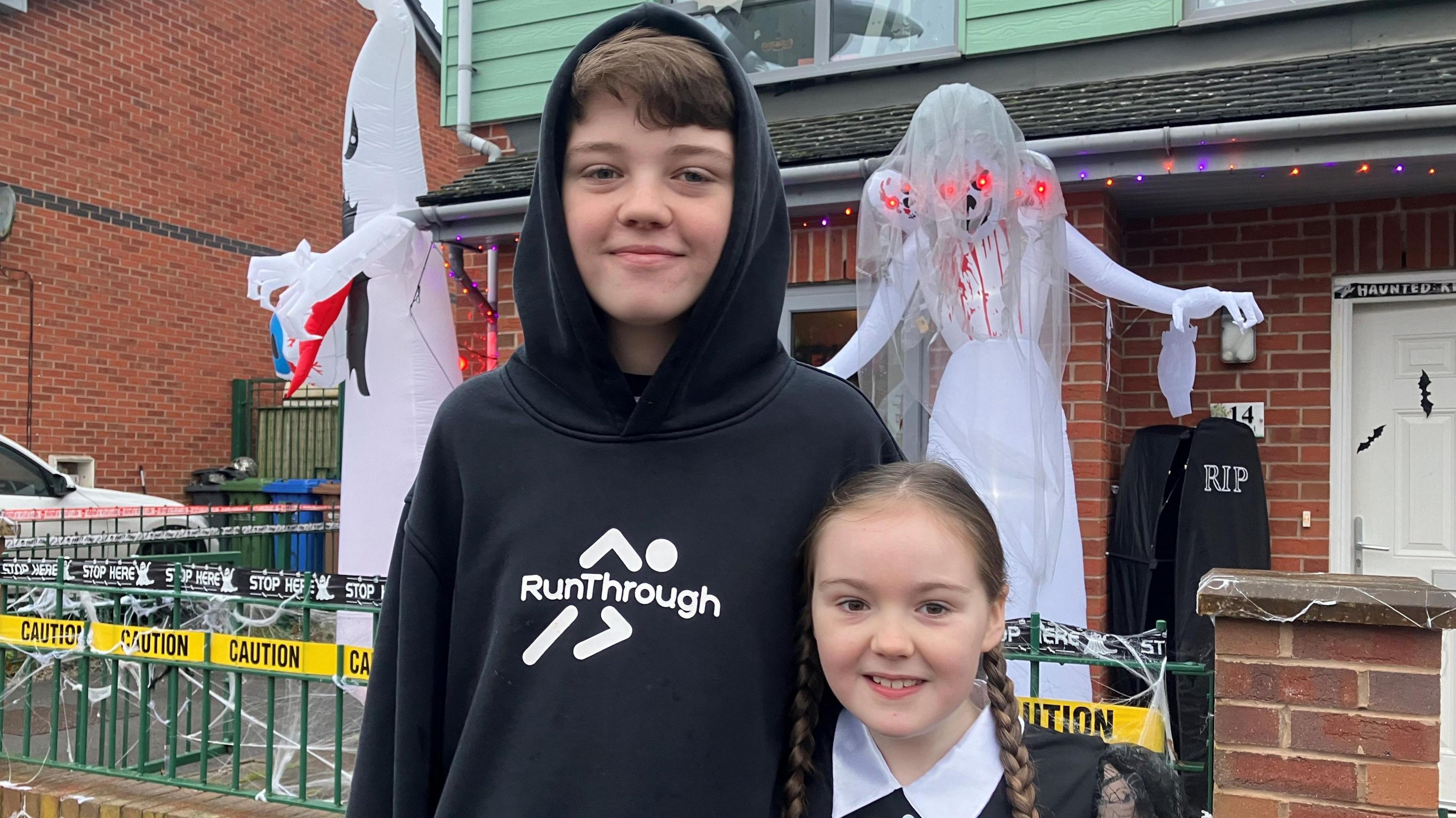 Photo of Matthew (11) and Hannah (8) Thaell outside their home with Halloween decorations